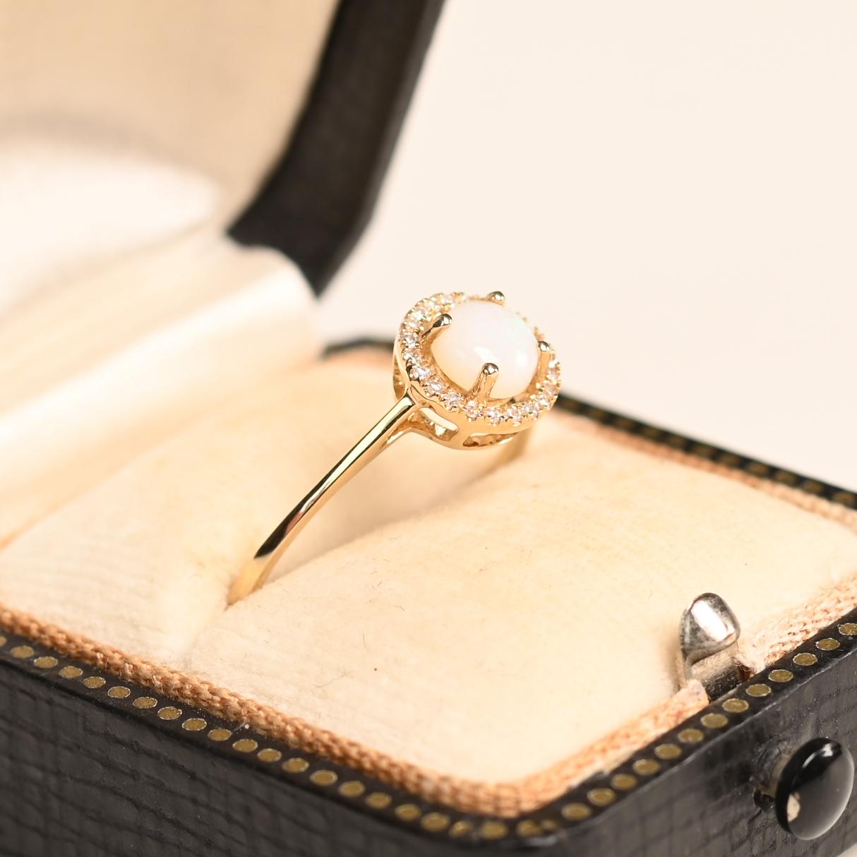 Questo squisito anello di fidanzamento mette in mostra un affascinante opale australiano da circa 0,30 carati al centro, incastonato saldamente in un'elegante montatura. Conosciuto per il suo ipnotico gioco di colori, l'opale presenta lampi di