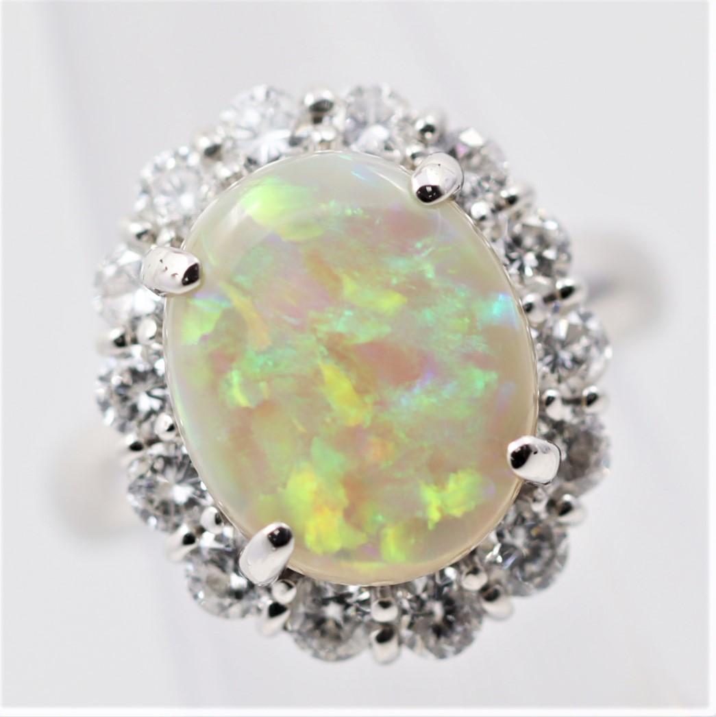 A fine and natural Australian opal takes center stage of this lovely platinum made ring. The opal weighs 3.59 carats and has excellent play-of-color as large bright flashes of green, blue, yellow, and orange can be seen on the stone. Its strong