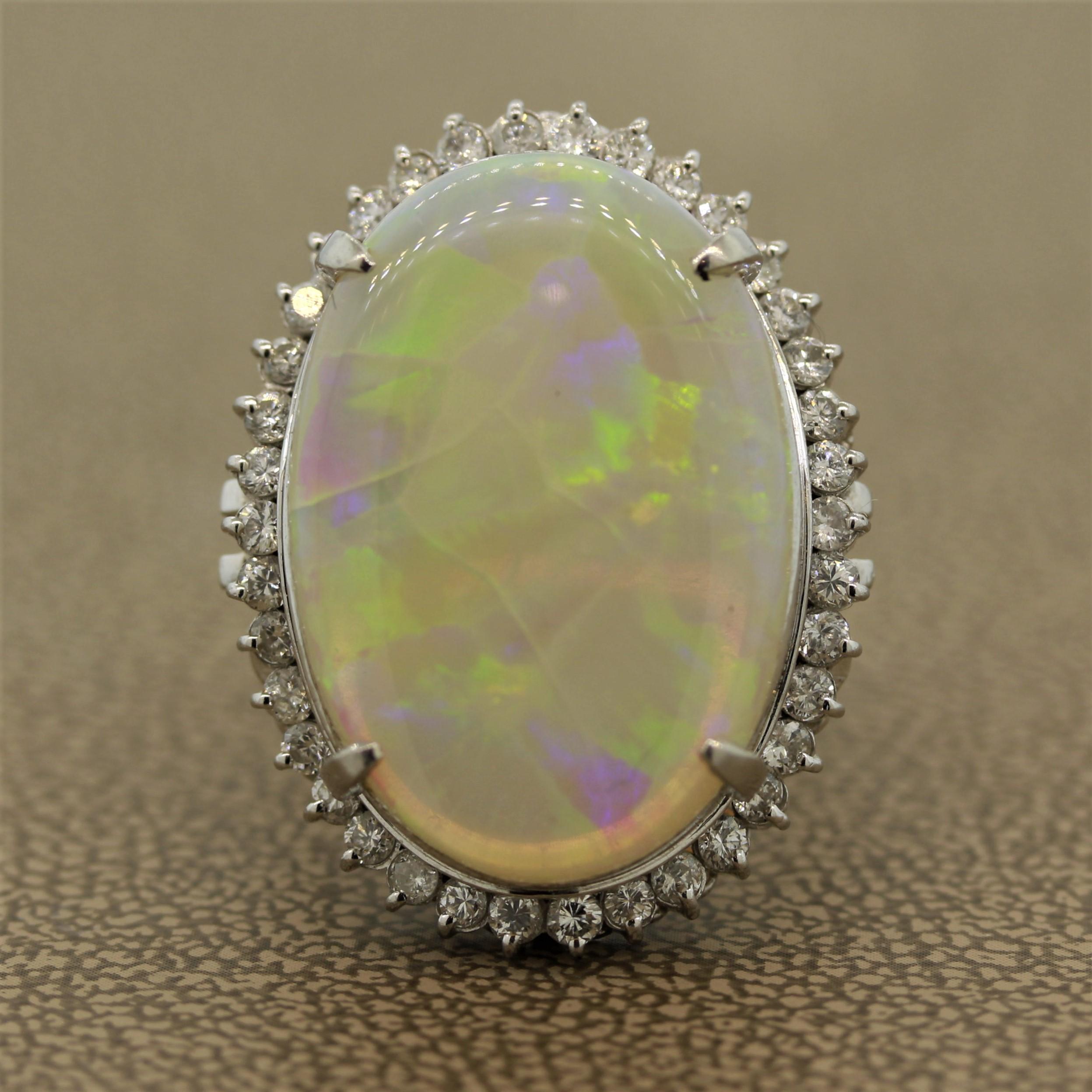 A large white Australian opal takes center stage weighing in at 11.67 carats. It shows bright flashes of green, blue, yellow, and orange. It is accented by 0.88 carats of round brilliant cut diamonds set around the opal making a halo. Hand
