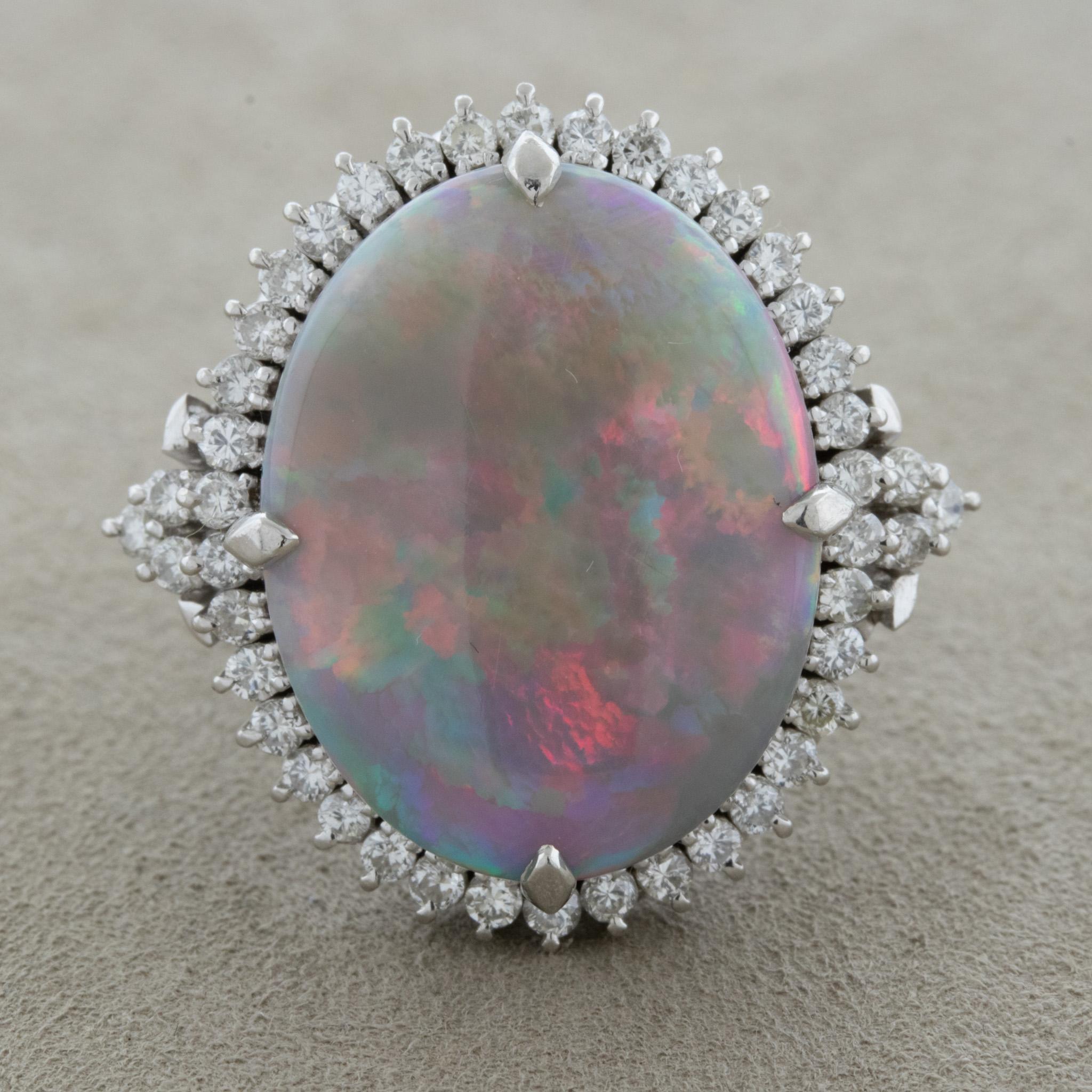 Une grande et impressionnante opale australienne pesant 9,37 carats occupe le centre de la scène et fait le spectacle ! Il présente un grand jeu de couleurs, car le rouge, ainsi que le bleu et le vert, clignotent sur la pierre. Elle est complétée