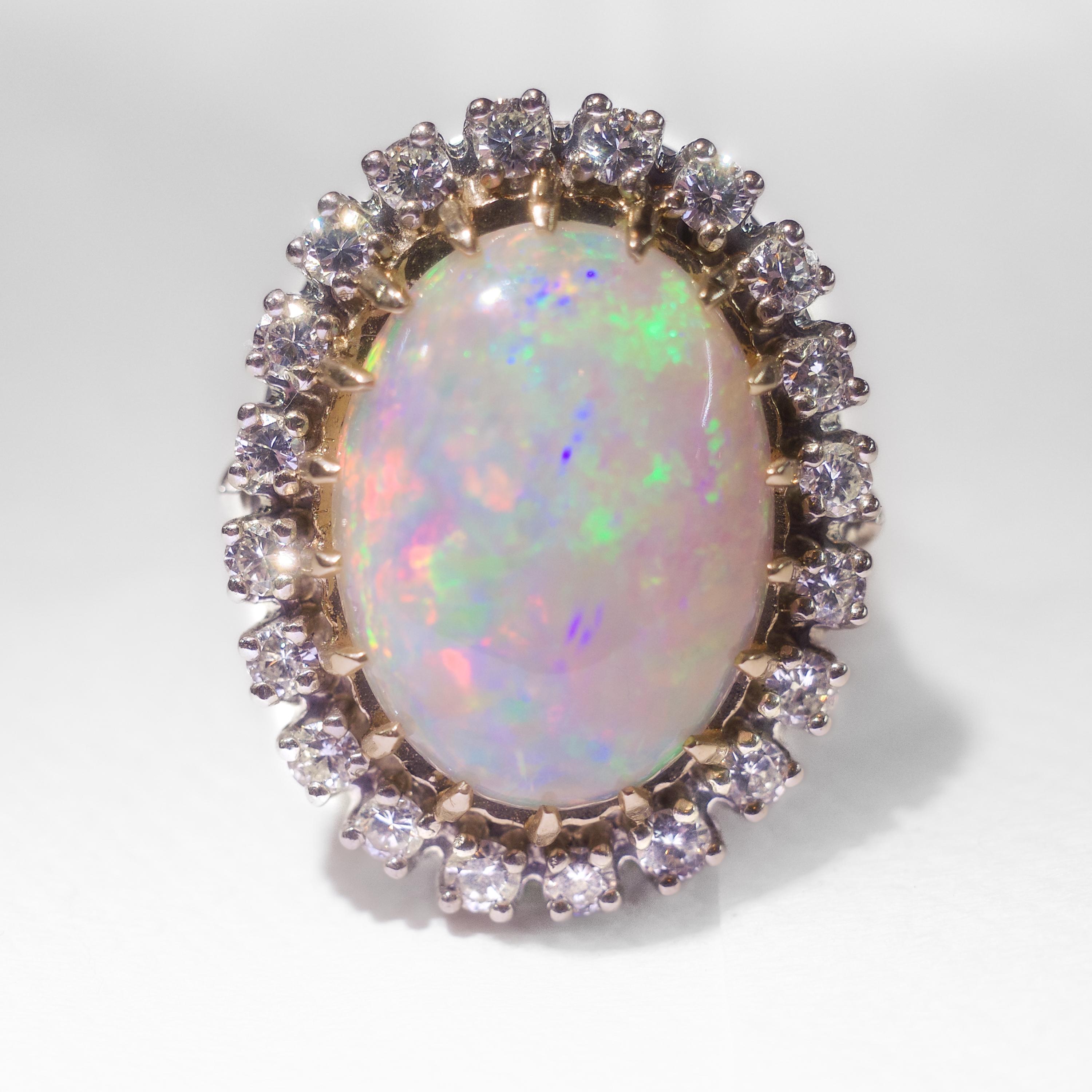 This gorgeous -and huge- opal and diamond halo ring features a brilliantly colorful, solid and natural opal from Australia that is consistent with opals from the mines in Coober Pedy, Australia. Featuring brilliant flashes of blue, purple, red,