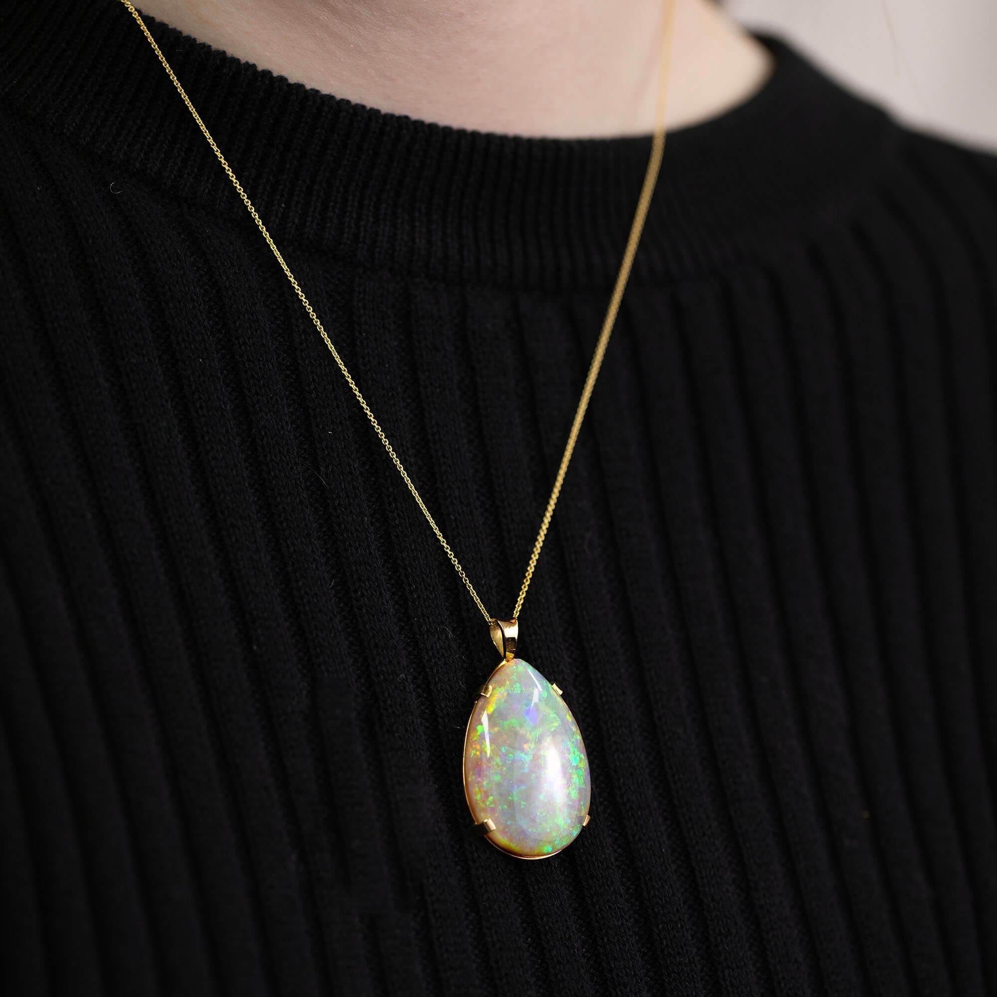 One handmade 18k yellow gold, solid Australian opal pear-shaped pendant. The opal is set in a four claw setting and has a plain runner a chain.

Gemstone: One (32 x 22 x 6.5mm) solid pear-shaped solid light opaque cabochon opal, class 1, with fine