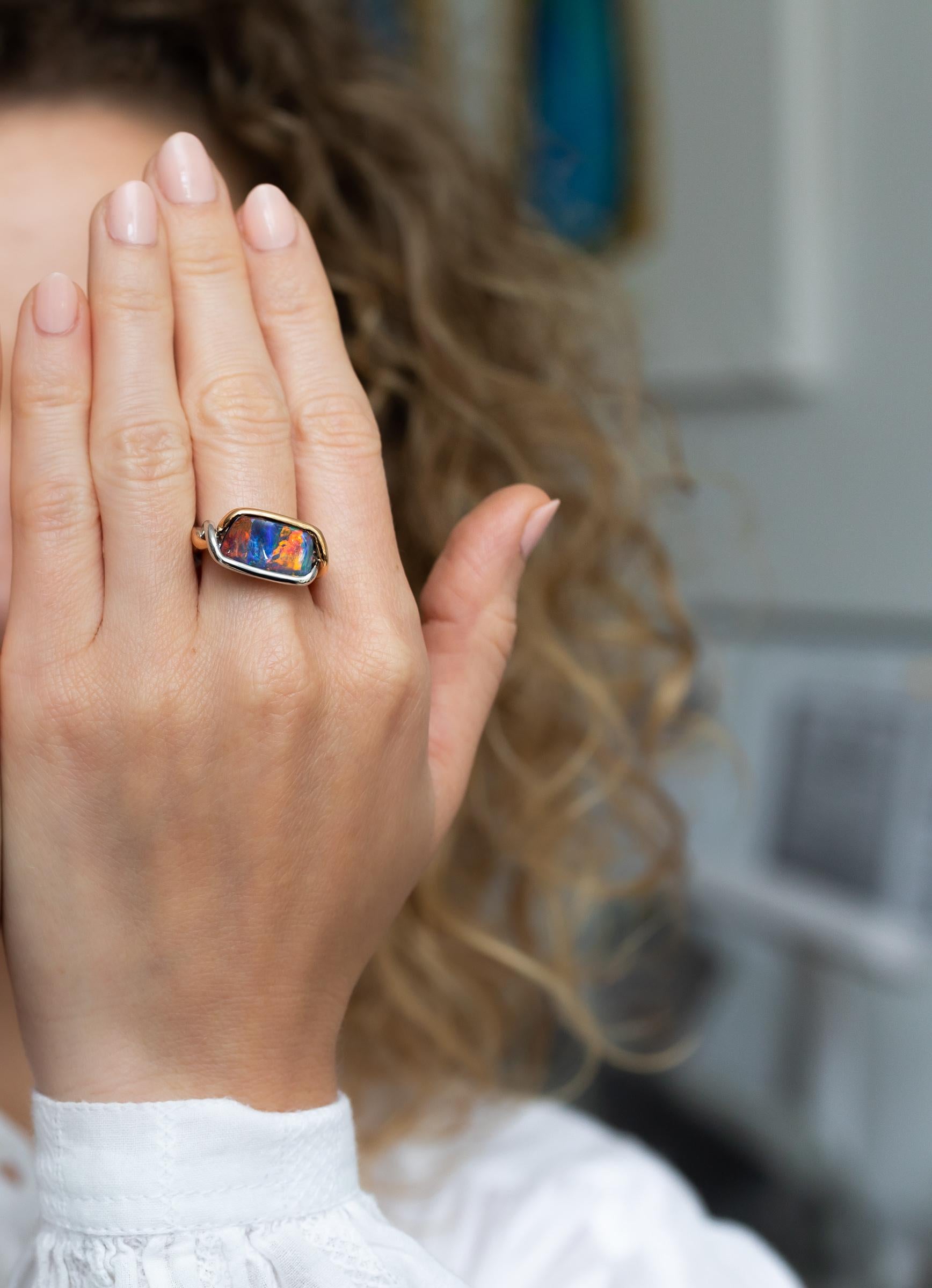 “Under the Tuscan Sun” is a lingering memory of Chianti, warm sunny days and bright blue skies. The striking 4.21 carat boulder opal is embraced by an unusual rose and white gold twist. The ribbon-flash pattern of bright reds, burnished oranges,