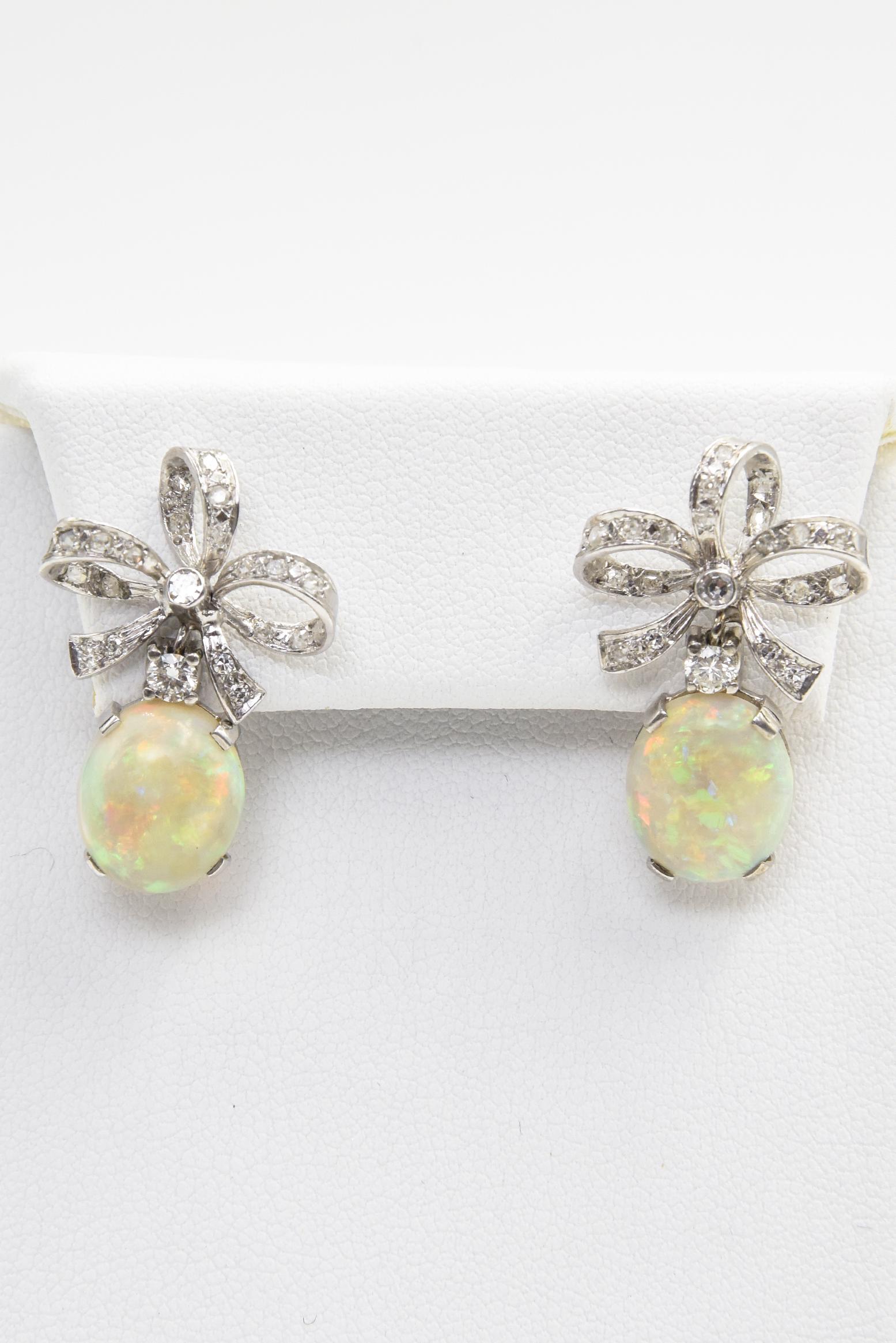Gorgeous Australian opal with incredible blue, green, red and yellow play of color dangling from a diamond three dimensional bow set in 14k white gold.  The opals measure approximately 10mm x 12 mm.  The earrings measure 1.06