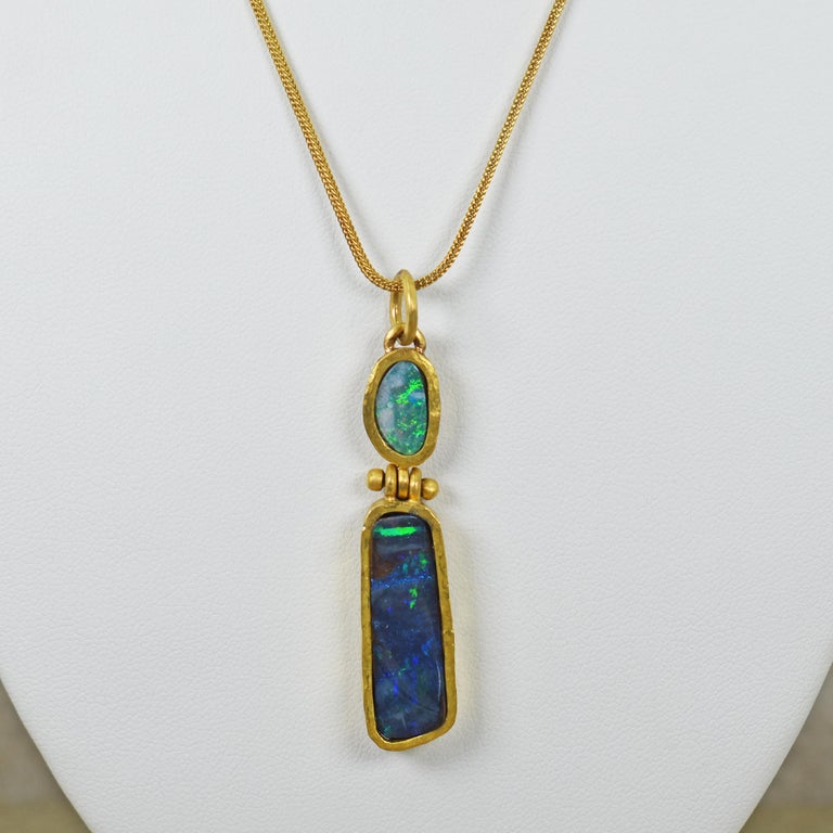 Gorgeous green and blue Australian Opals in a hand forged 22k yellow gold hinged pendant. Opal two stone pendant is on an 18k gold 18 inch Foxtail chain necklace. Pendant, including bail, is 2.25 inches in length. The hinge connection is functional,