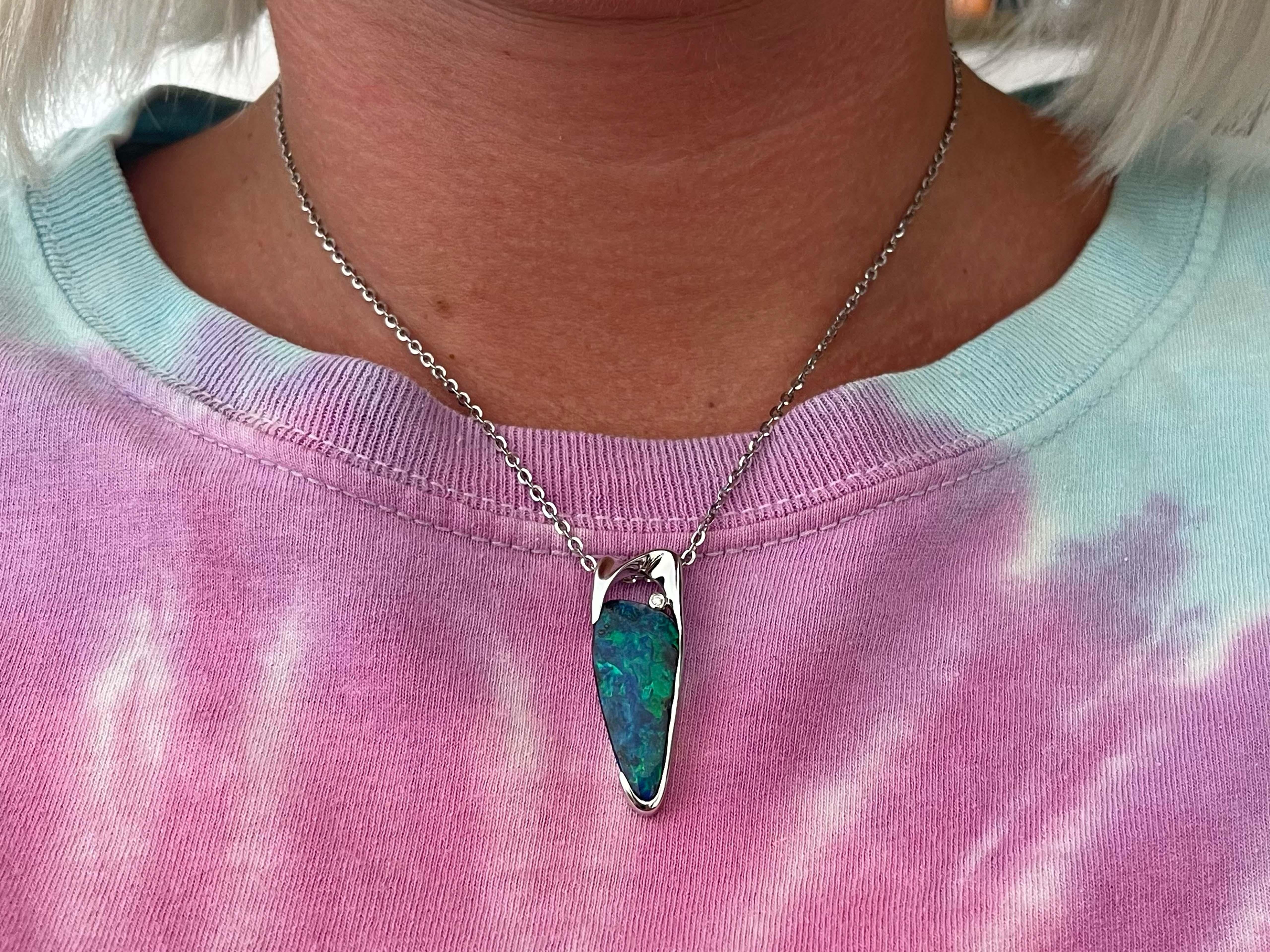 This unique piece of jewelry is one-of-a-kind. At its center is a stunning blue green opal, resembling the Northern lights of Alaska, a truly rare phenomenon, this opal is much the same in its rare stunning color play of deep blue and electric green