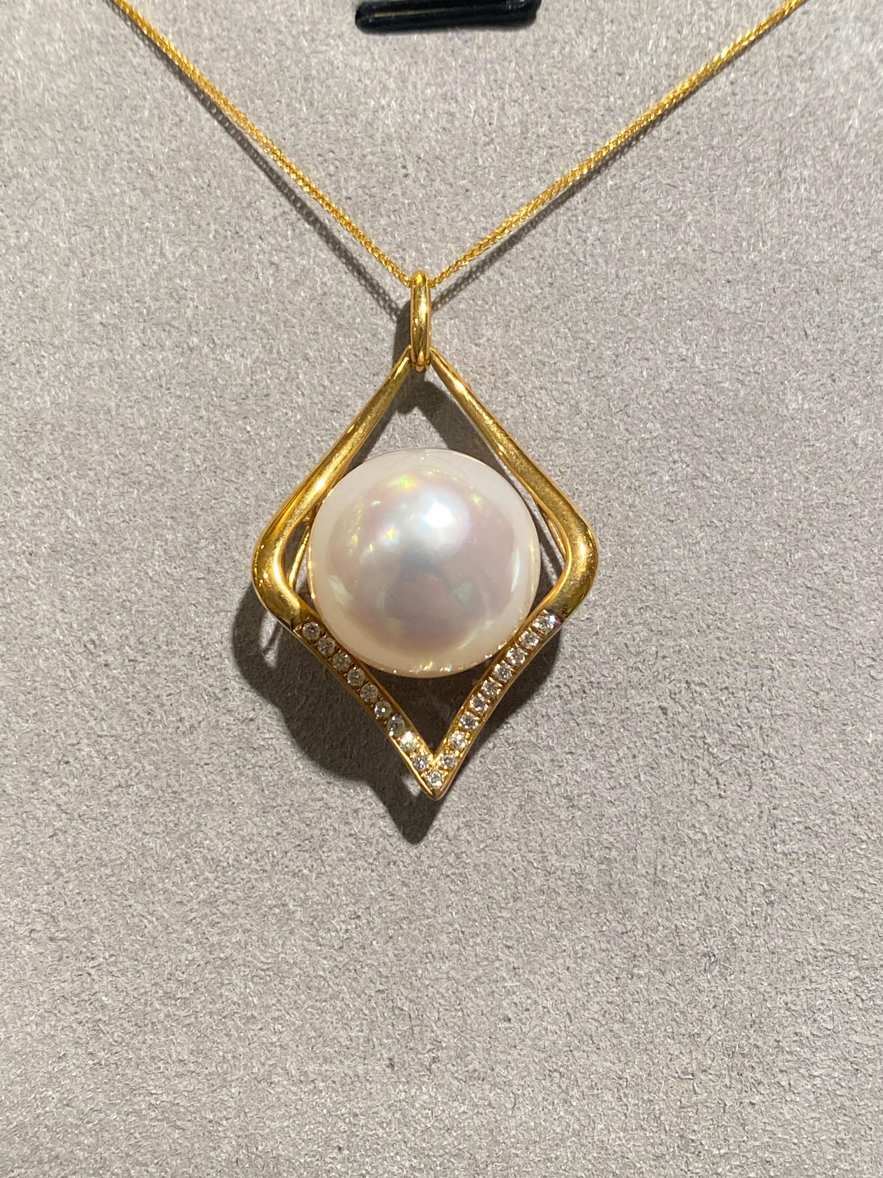 A White Australian South Sea Pearl and diamond pendant in 18k Yellow gold. The pendant is of kite shape with diamonds pave at the opposite side of the bale. The pearl is of button shape and measuring 15.5mm x 16mm. The pearl is white in colour with