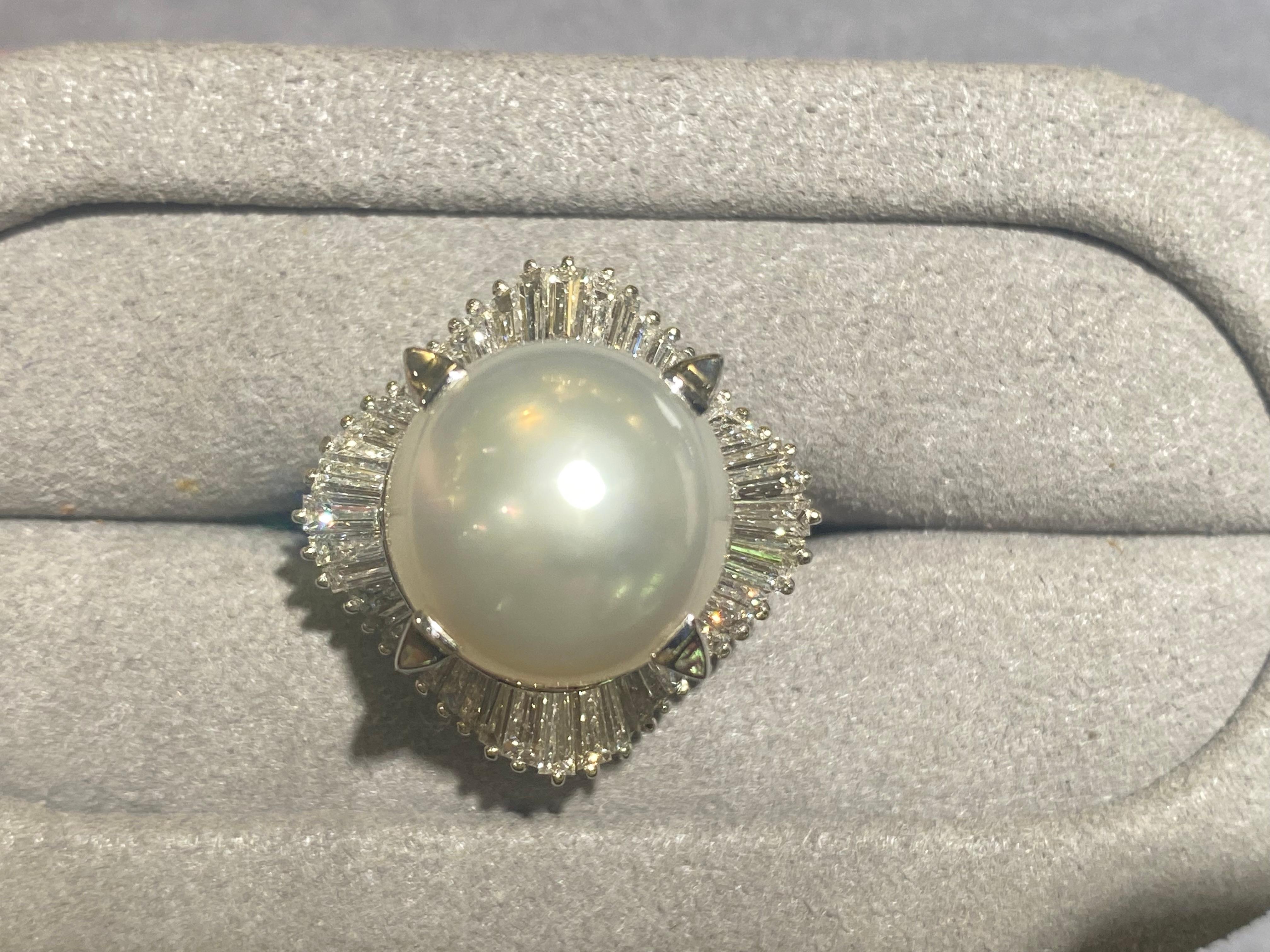 A 13.3 mm White Australian South Sea Pearl and Diamond Ring in Pt 900 Platinum. The White Australian South Sea pearl is secured by 4 long claws that are rising from the surface of the ballerina set baguette diamonds. It is a big statement pearl ring