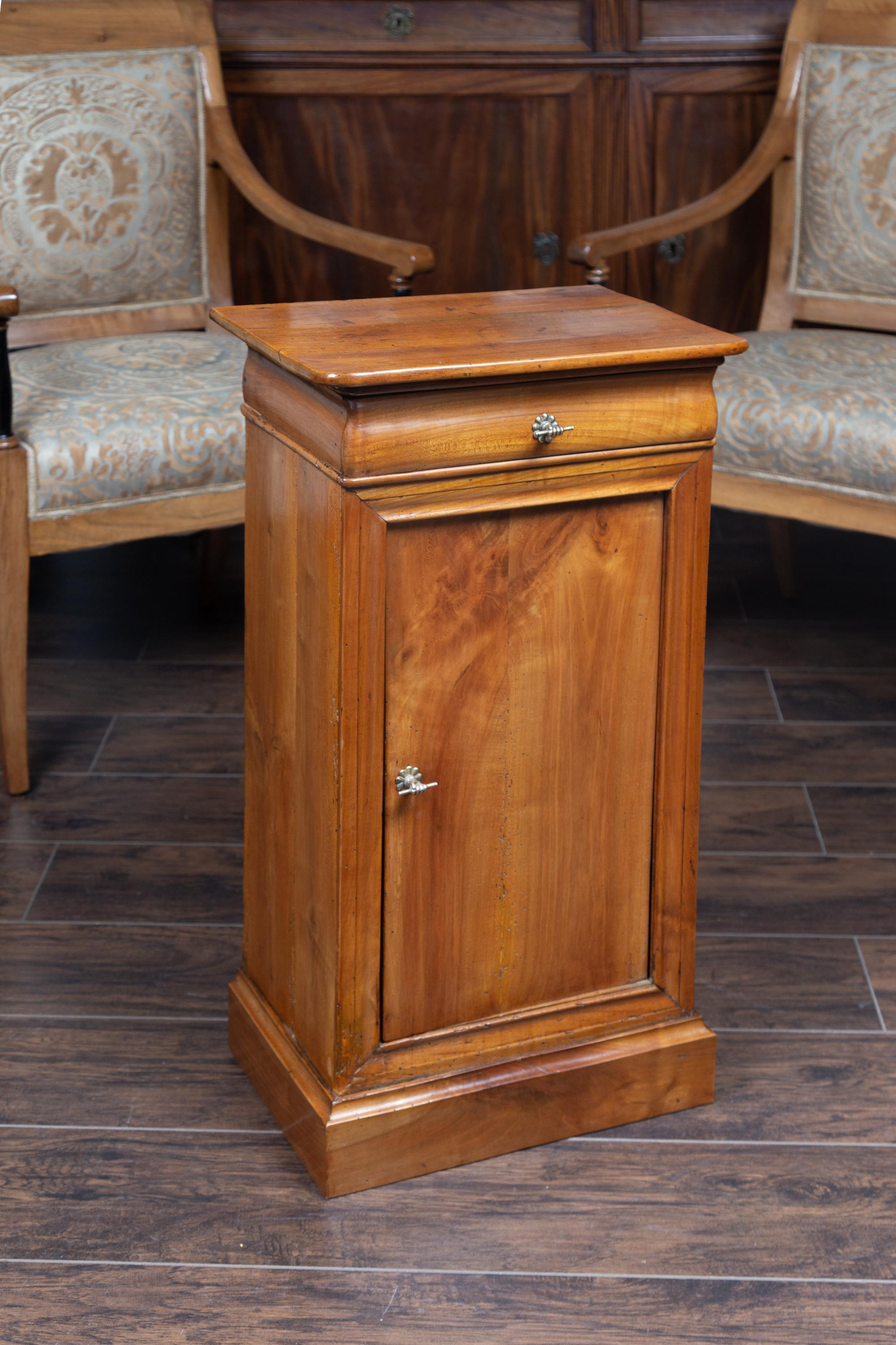 An Austrian Biedermeier style walnut bedside cabinet from the late 19th century, with single drawer, door and brass hand pulls. Born in Austria during the second half of the 19th century, this exquisite Biedermeier bedside cabinet features a