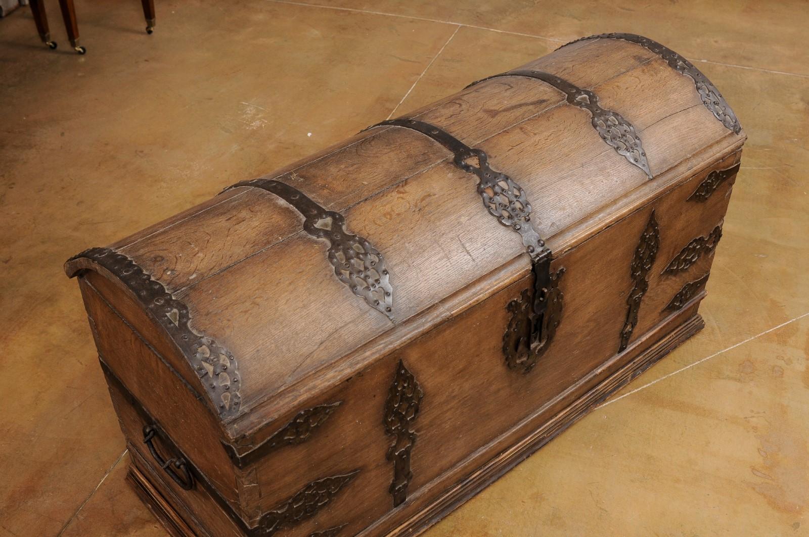 An Austrian oak trunk from the 18th century, with domed lid, ornate iron hardware and lateral handles. Created in Austria during the Habsburg Empire in the 18th century, this oak trunk features a rectangular silhouette topped by a domed lid. This
