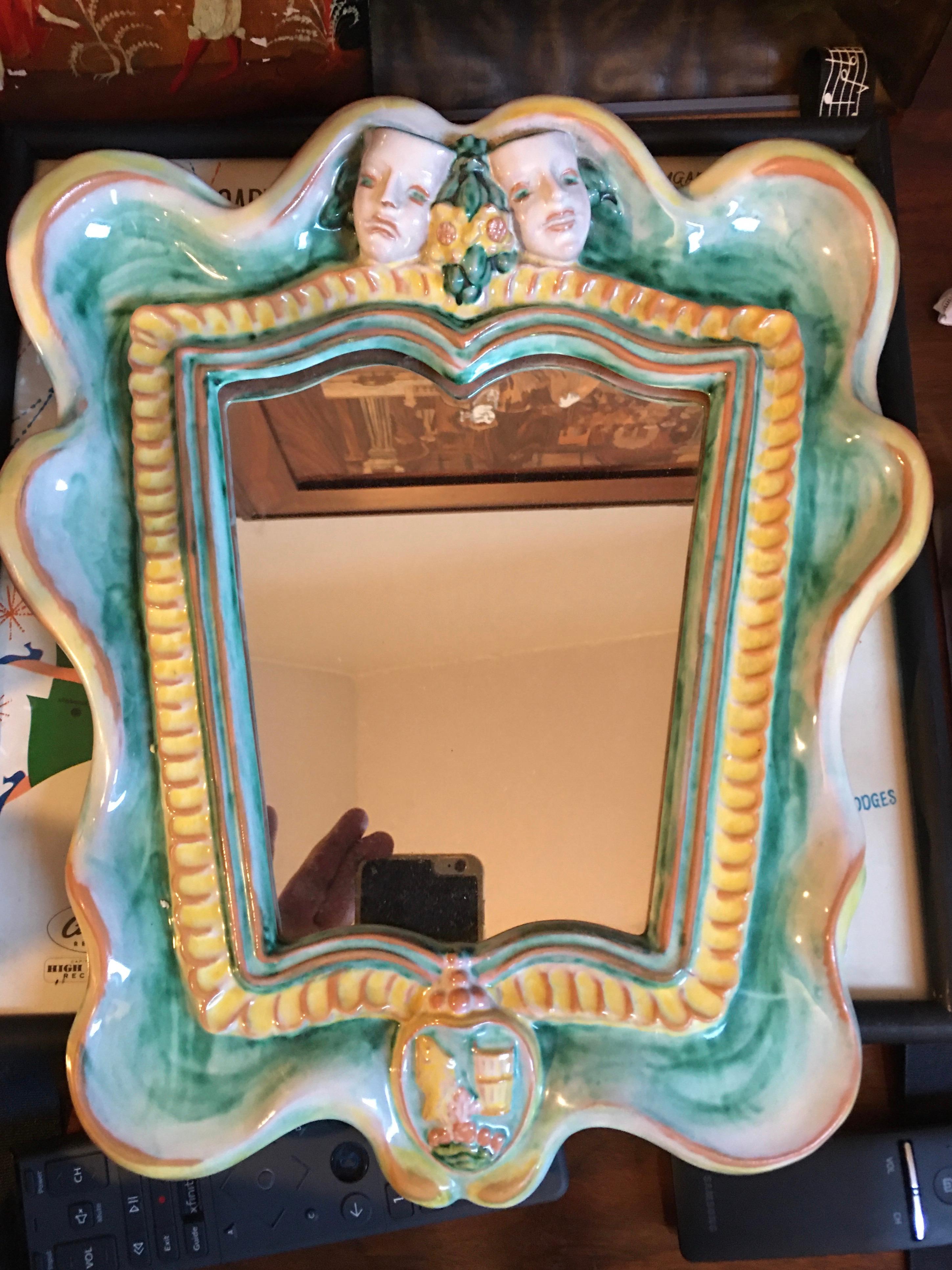 Franz Schleiss (1884-1969) for Gmundner Keramic, Austria 1930s wall mirror, Model 2140, green, yellow and red glaze.
Shield-shaped frame, above two sculpted theatrical masks with a bouquet of flowers below a decorative coat of arms.

  