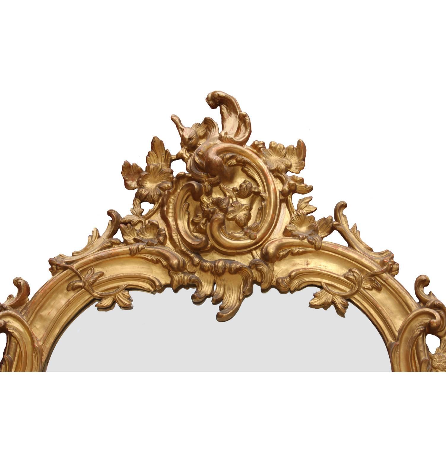 A fine Austrian 19th century Rococo style giltwood carved and Gesso overmantel mirror frame with shelves. The ornately carved floral and scrolled crown centred with a mirror plate and a cone-shaped shelf, all above a three-sectional mirror frame