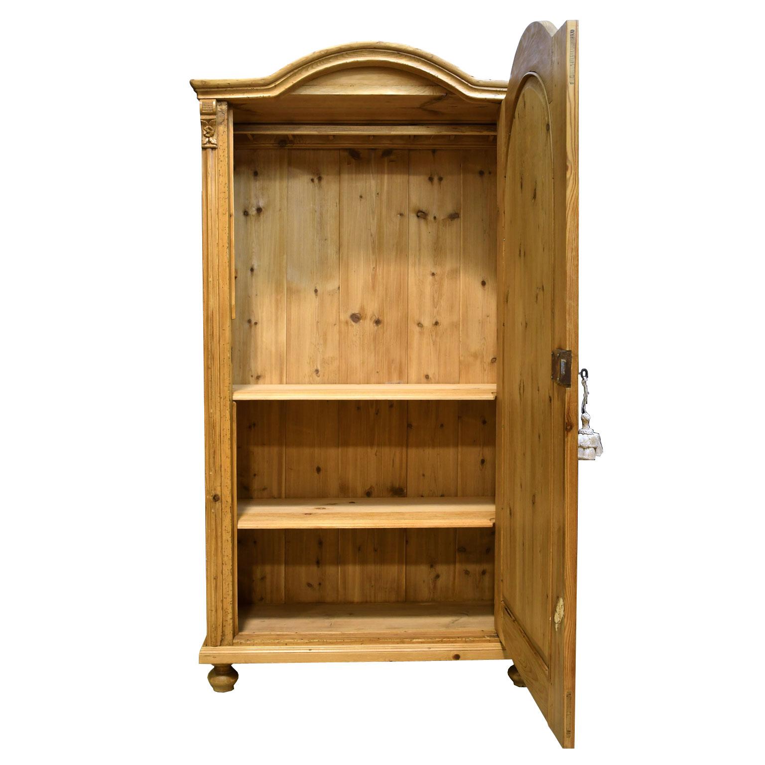 A charming pine armoire with arched top and carved rose embellishments on the top corners flanking the single door. Hungary or Austria, circa 1830. Offers new shelving: two that are fixed, with brackets for the third, and original working lock, with