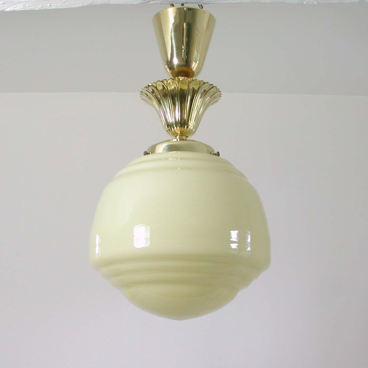 This late Art Deco ceiling light was designed and manufactured in Austria in the early 1940s. It has got an ivory colored opaline glass shade and brass details. All brass parts have been polished and the lamp has been rewired.