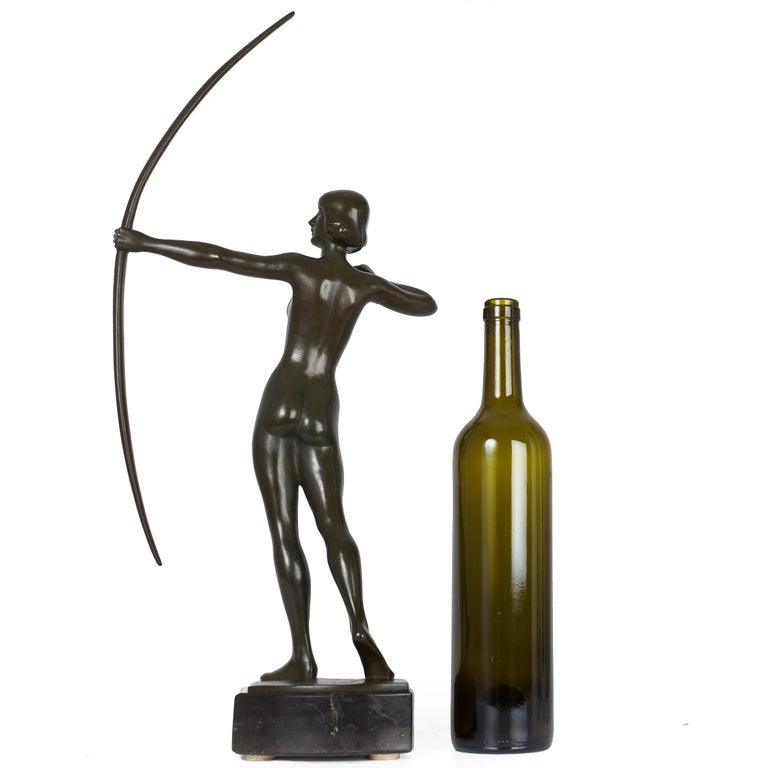 An exquisite Art Deco bronze model of Diana the Huntress circa the 1930s, it is a sleek and minimalist depiction of the goddess raising her bow with her sights set on a distant target. It is finished in a fine dark green patination under beeswax and