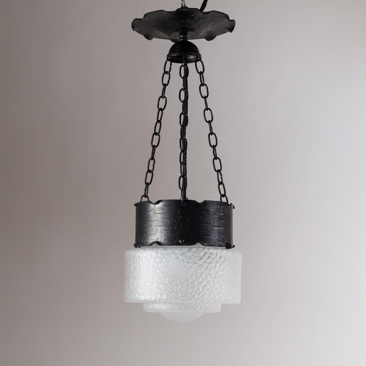Art Deco pendant from Austria, circa 1930. Forged and hammered steel or iron hardware with a stunning textured satin glass diffuser. The tiered glass has an intricate abstract texture that is often referred to as 