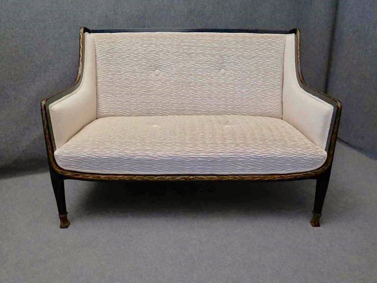 Sofa of the early 1900s. Completely covered in fabric except for a fine frame that runs along the entire edge of the armrests and seat. The frame is made of wood polished in black lacquer, with in the central part a manual work carved in wood and