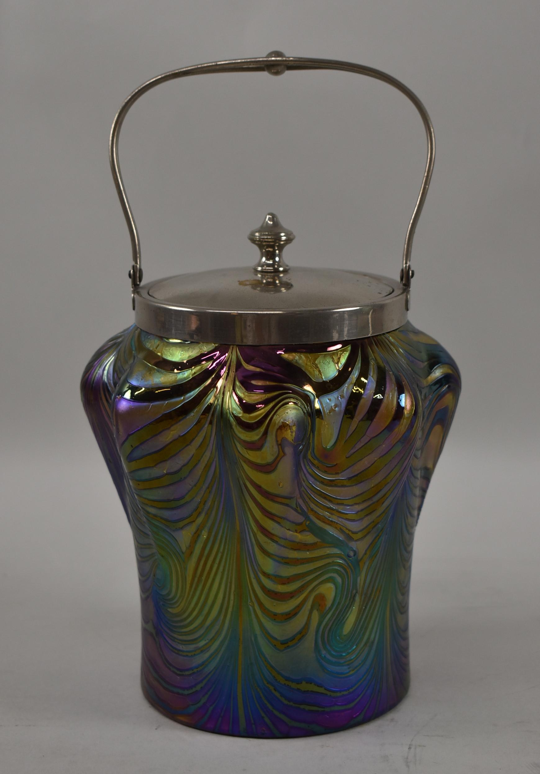 Austrian art glass biscuit jar in iridescent shades of purple, blue, green and gold. Lid and handle are silver plated. Beautiful swirl design. Very nice condition. Measures: 9 3/4