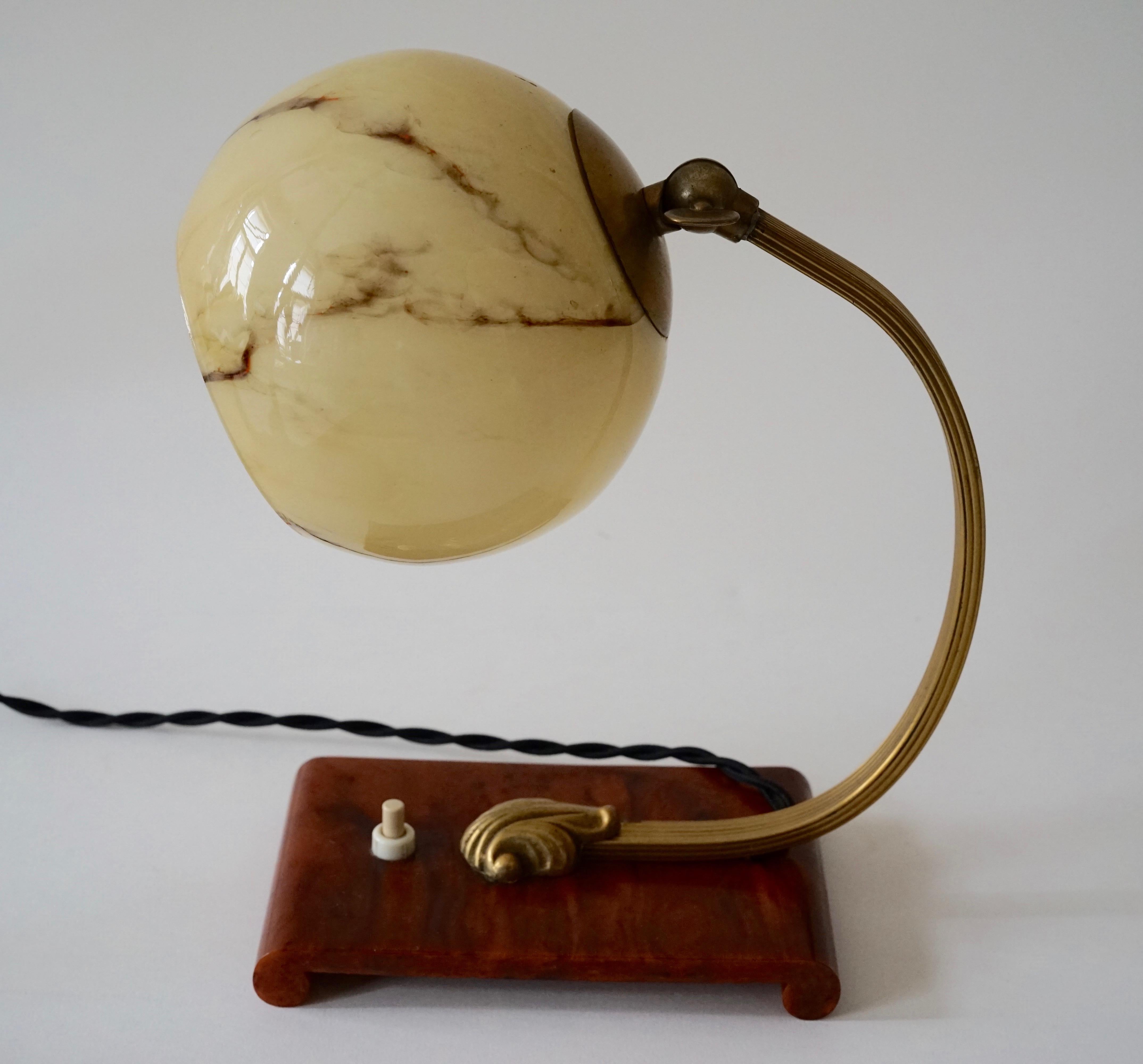 This vintage table or bedside lamp was made in Austria in the 1920s, during the Artdeco period.
The lamp is made of brass with a bakelite base. The shade, is marbleised ,opaline glass and is adjustable.
The electric cable has been replaced with a