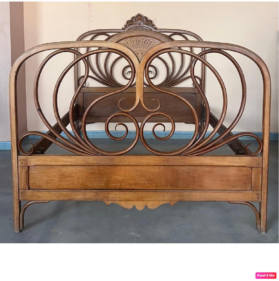 Conçu par J & J Kohn, ce lit en bois courbé teinté d'acajou présente une tête et un pied de lit incurvés gonflés de rinceaux décoratifs.  
J & J Kohn, No. 876, Catalogue 1900.

Hauteur du sol aux rails : 15,75 pouces
Hauteur de la tête de lit :