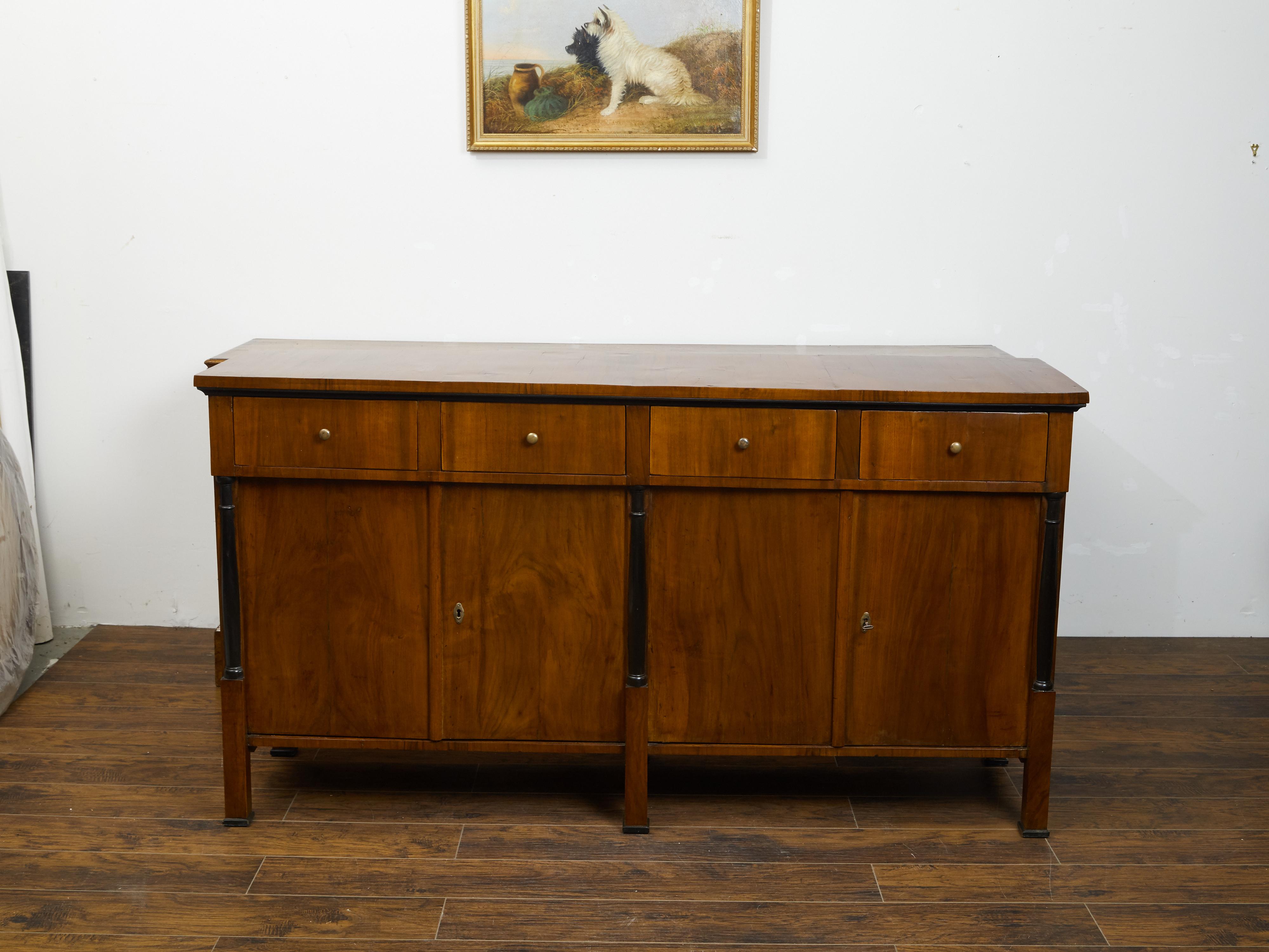 An Austrian Biedermeier period walnut sideboard from the mid 19th century, with four drawers, two pairs of double doors and ebonized columns. Created in Austria during the second quarter of the 19th century, this Biedermeier sideboard features a