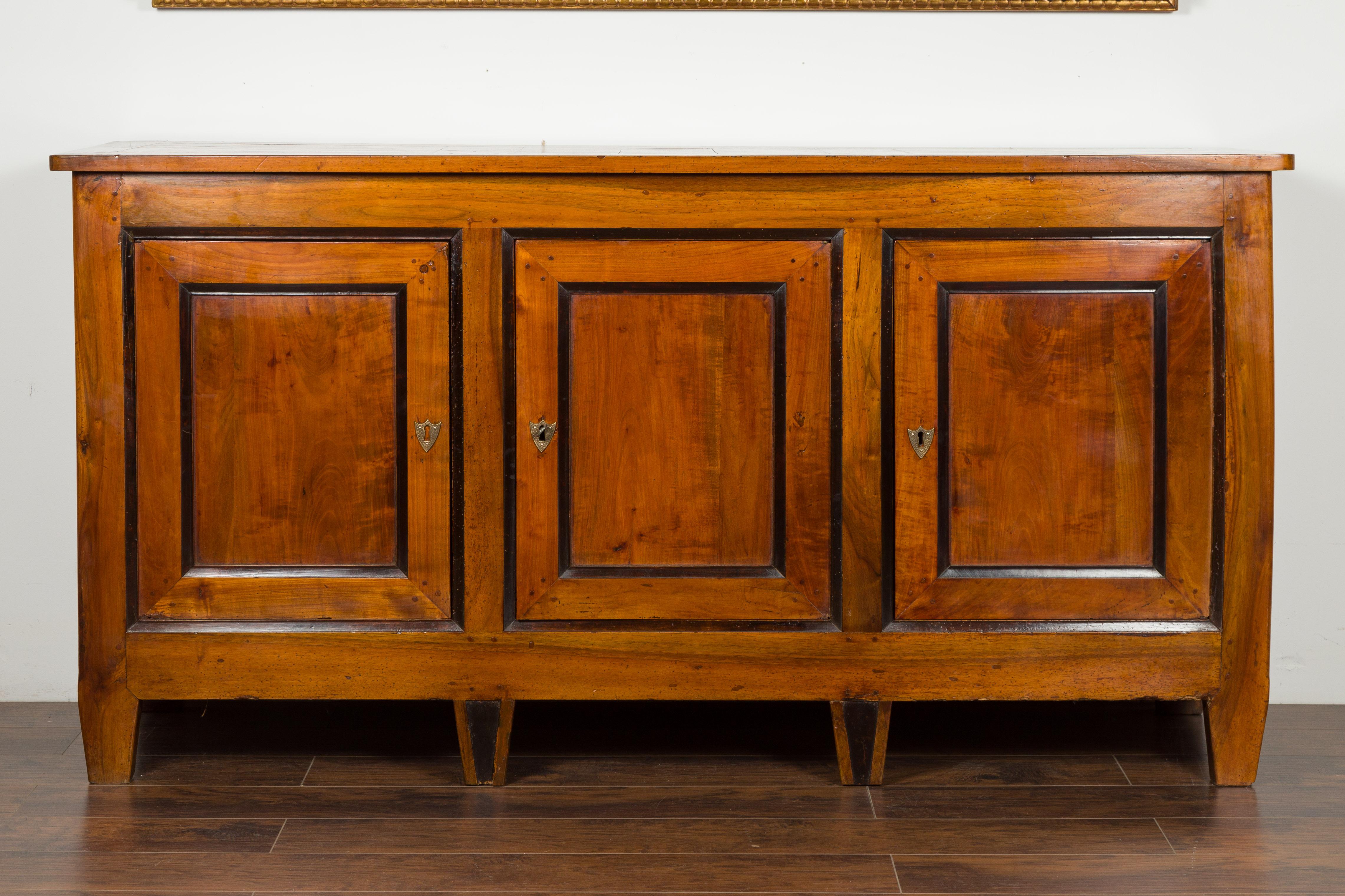 An Austrian Biedermeier period walnut three-door enfilade from the mid-19th century, with ebonized accents. Created in Austria during the second quarter of the 19th century, this walnut enfilade features a rectangular planked top sitting above three