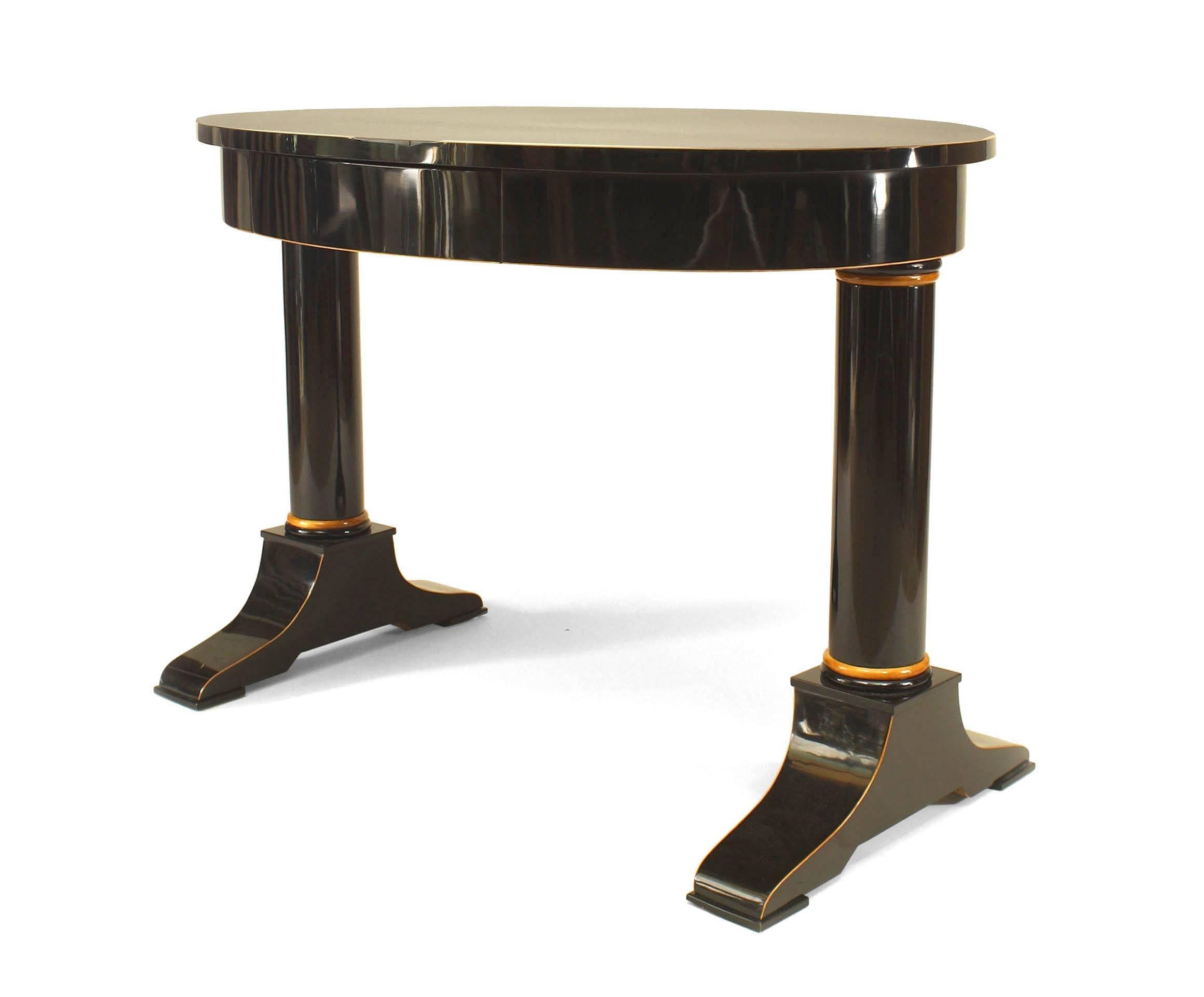 Austrian Biedermeier (circa 1825) ebonized oval top table desk with maple trim and pearwood inlaid banding and supported on 2 columns with a center drawer.
