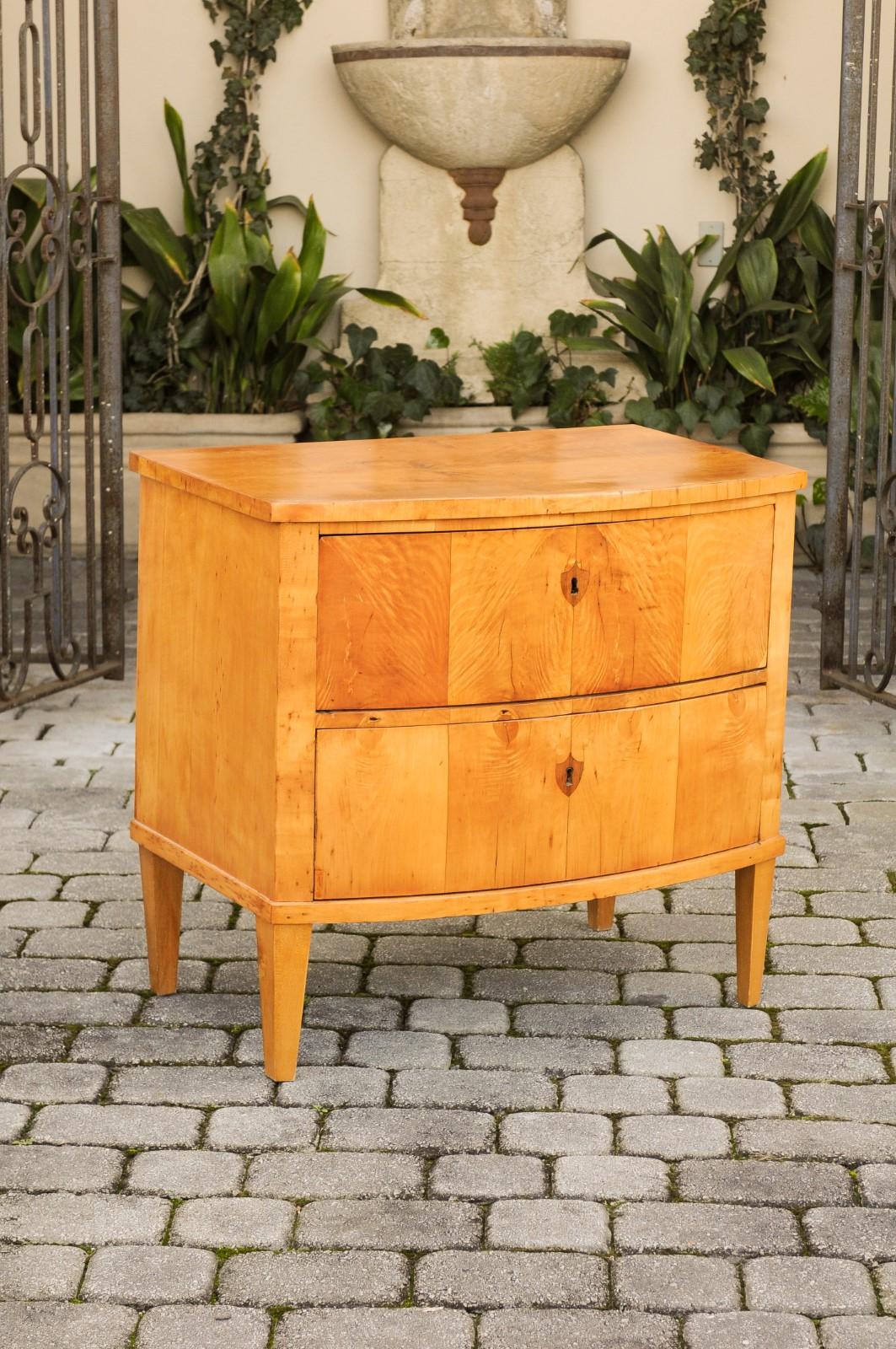 An Austrian Biedermeier two-drawer commode from the late 19th century, with bow front and tapered feet. Born in Imperial Austria during the third quarter of the 19th century, this elegant Biedermeier chest features a rectangular top sitting above a