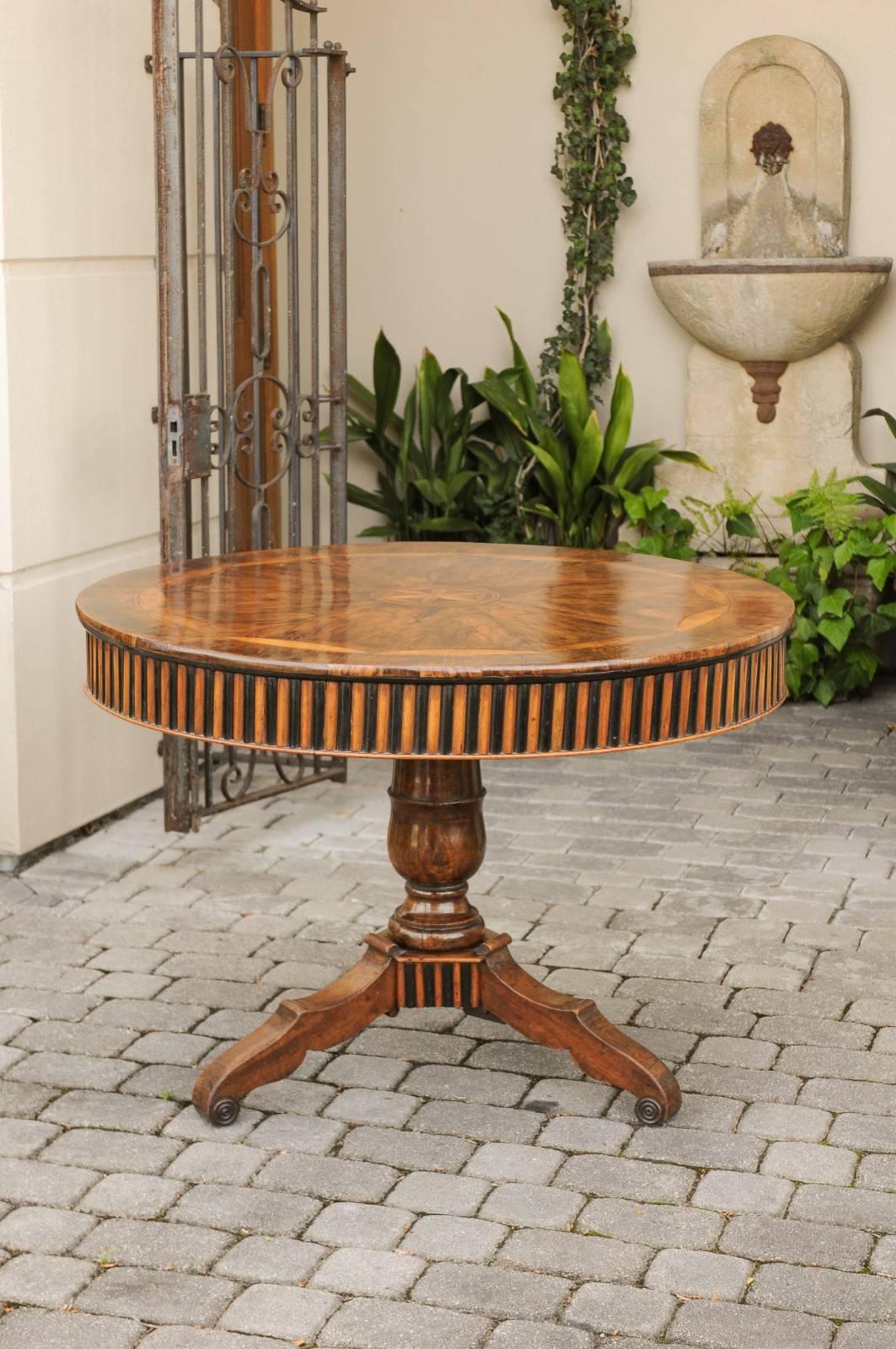 An Austrian round Biedermeier pedestal table of burl walnut from the late 19th century, with marquetry inlay and ebonized wood accents. Born in the second half of the 19th century, this Biedermeier table features an exquisite circular top, adorned