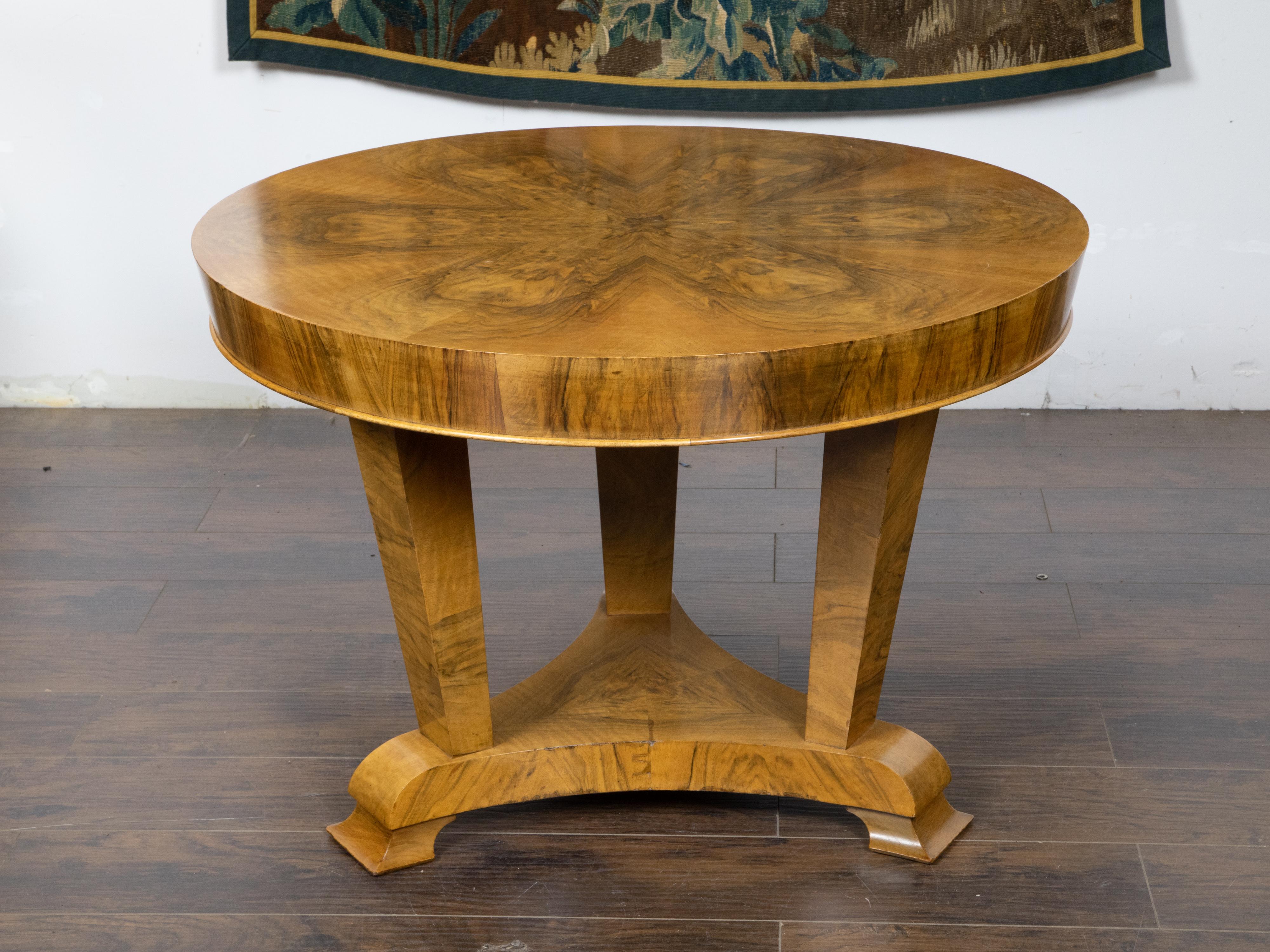 An Austrian Biedermeier period walnut center table from the mid 19th century, with butterfly veneered top, tripod base and scrolling feet. Created in Austria during the Biedermeier period in the second quarter of the 19th century, this center table