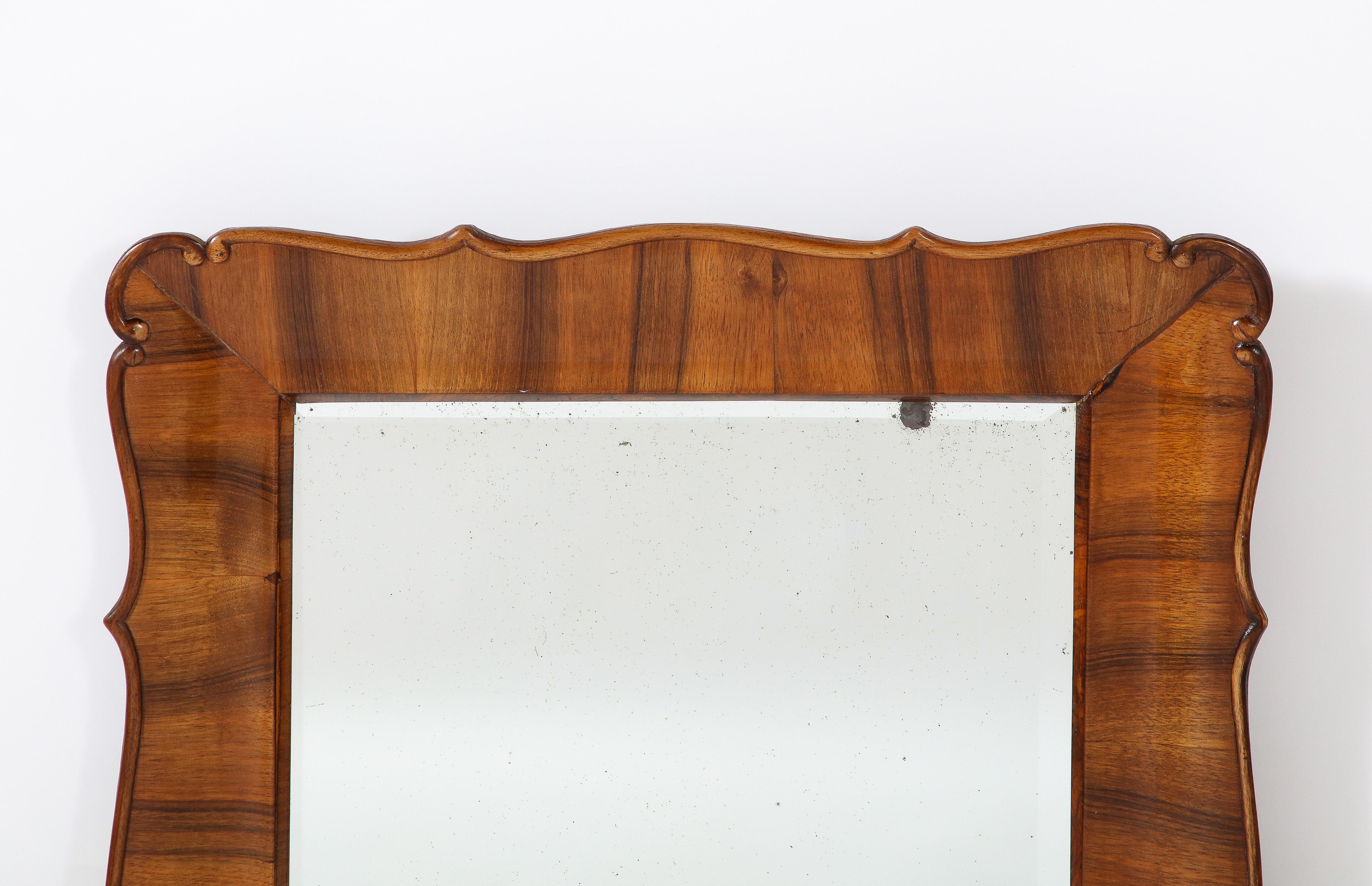 A rare and unique Austrian Biedermeier walnut framed mirror, with scalloped and scrolled hand-carved motif. Highly refined form and elegant design. The rich walnut grained wood so beautifully contrasts with the original beveled plate glass. All
