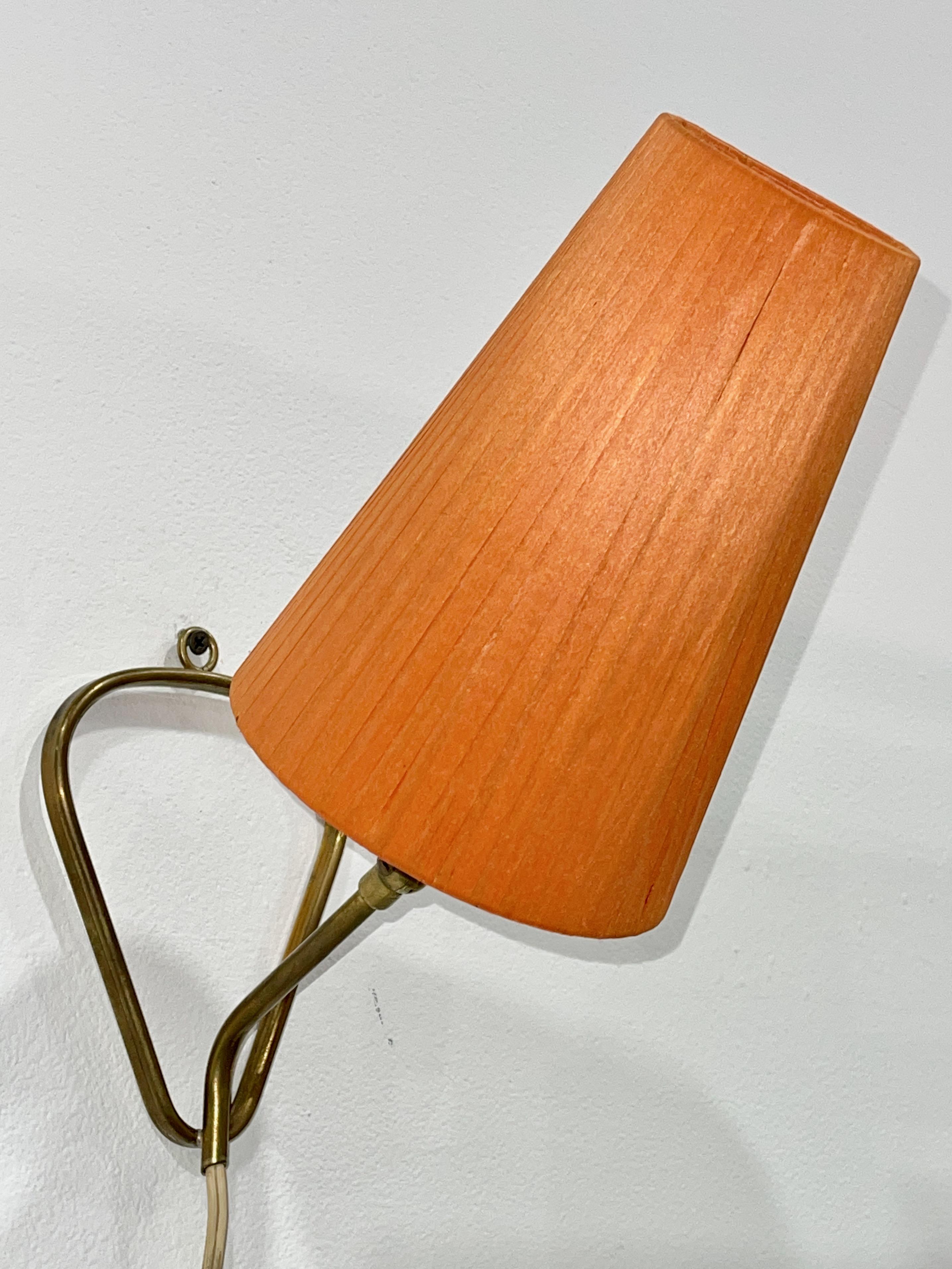 Chic petite convertible brass lamp from Austria, 1950's with articulating lamp head.  
Placement easily moved from table top to hanging on wall. 
Takes a single edison screw bulb.
Comes with orange conical uno ring lampshade.
Corded with inline