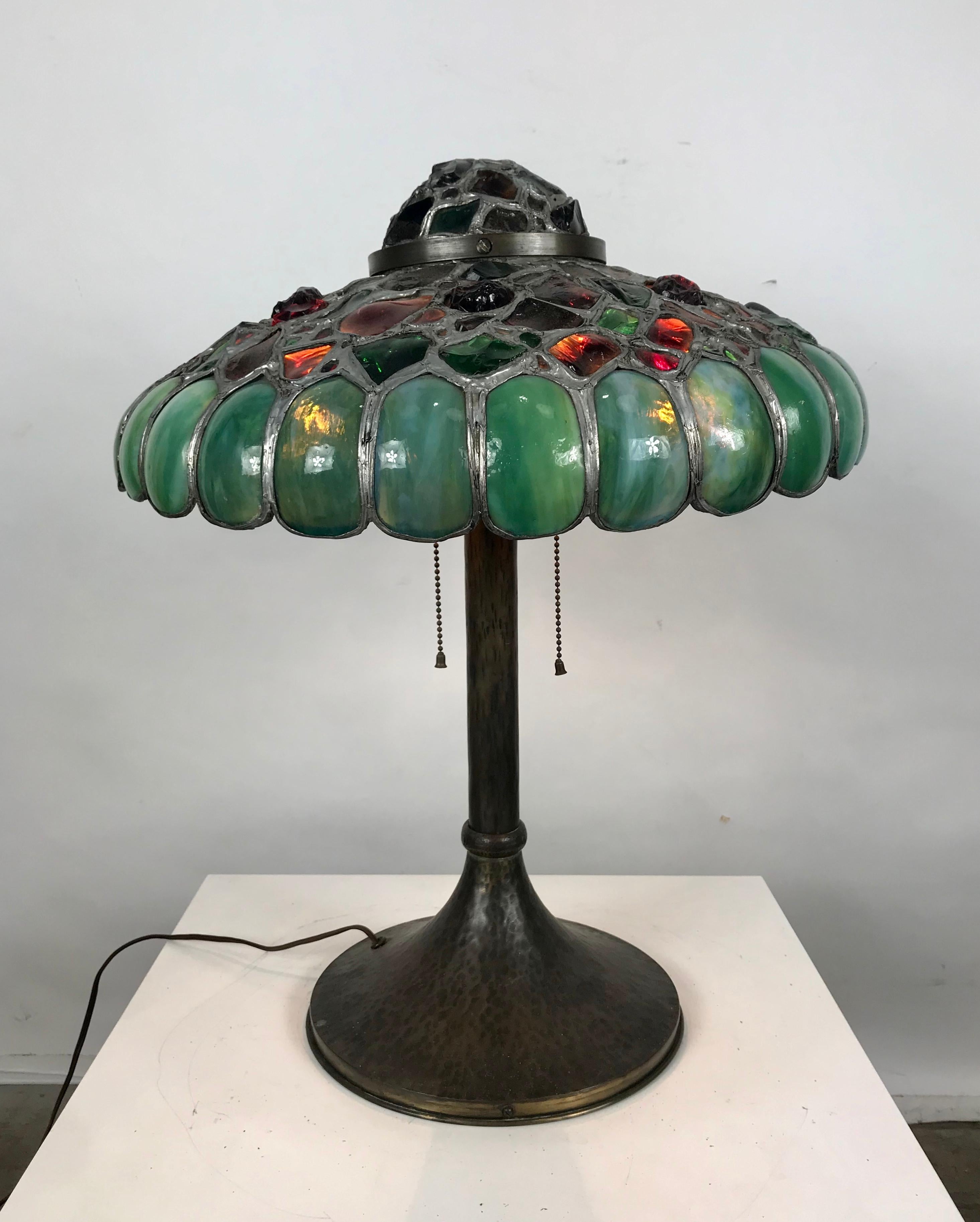 Austrian bronze and chunk jewel, slag glass table lamp. This incredibly colorful lamp is one of the more exotic examples of this style table lamp. The jewels are all handcut and light up with very vibrant colors. Classic form. Stunning example.