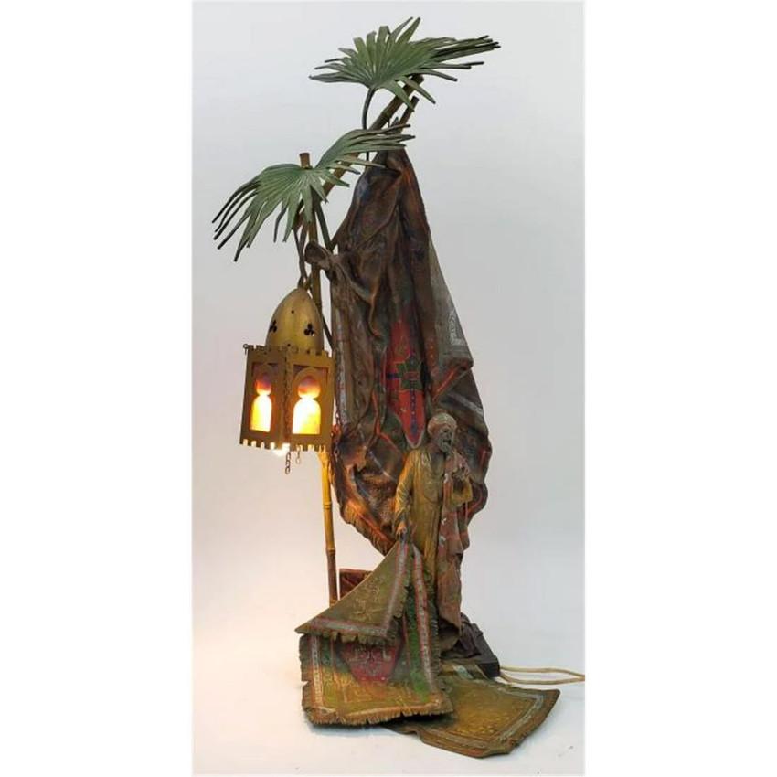Exceptionnelle grande lampe autrichienne en bronze polychrome représentant un marchand de tapis arabe debout à côté d'un grand palmier auquel est suspendue une lanterne. La lanterne contient du verre rouge et vert, ainsi que l'ampoule de la lampe,