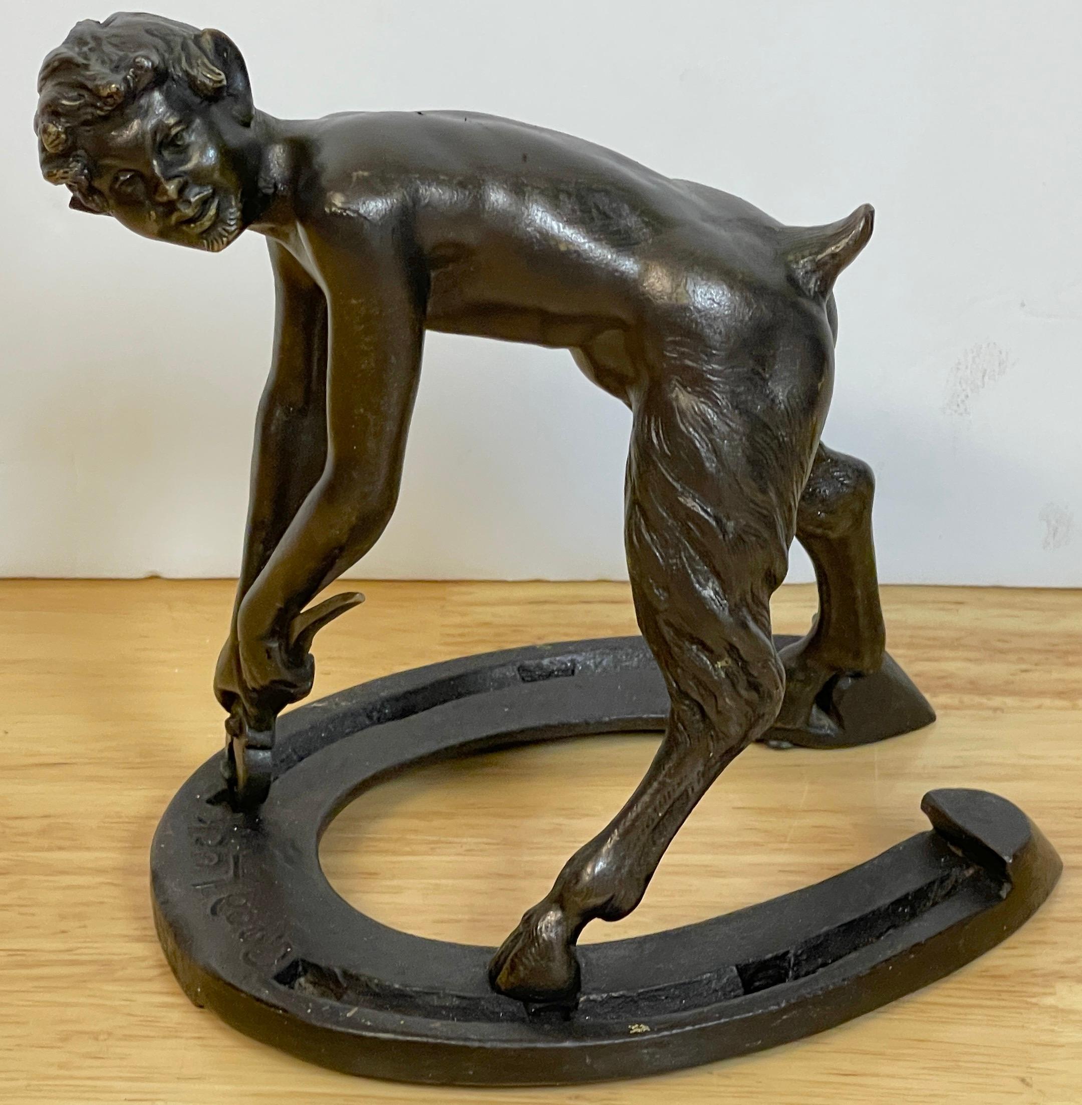 Austrian Bronze Satyr Allegory of Luck, Attributed to Bergman 
depicting a crouching satyr with pliers, pulling out the nails of a 'Good Luck' Horseshoe, numbered to the underside. 

