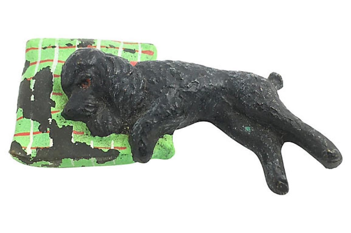Austrian cold-painted bronze figurine of a sleeping poodle on a green, red, and white checked pillow. No maker's mark. Extensive paint loss on pillow.