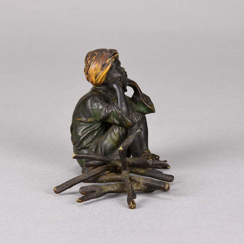 An excellent early 20th century cold painted Austrian bronze study of a young boy sat beside a pile of firewood with his head rested upon his hands in deep contemplation. The bronze with very fine colour and good hand chased surface detail, signed