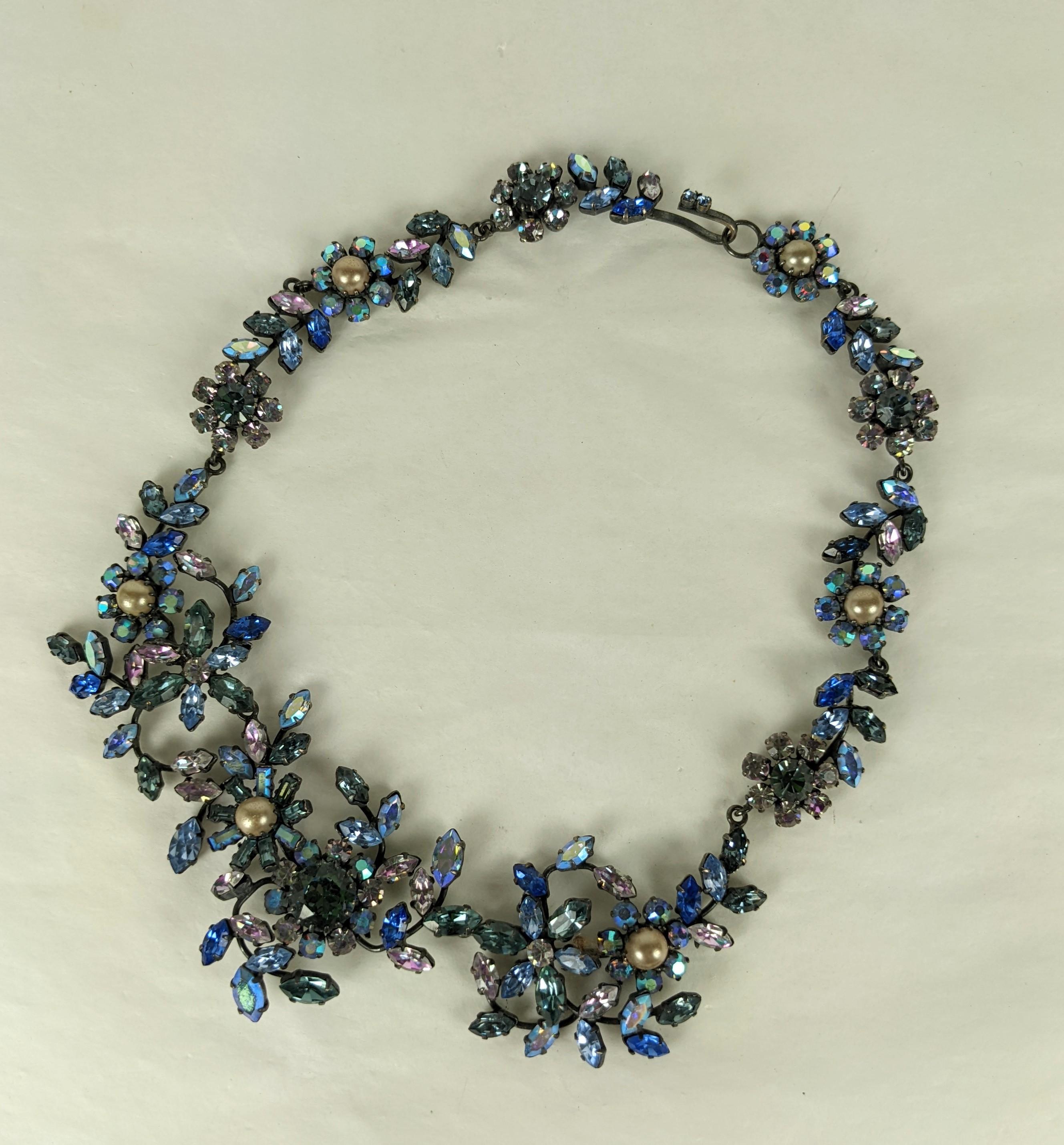 Austrian Crystal Aurora Garland style bib from the 1950's. Hand set vari color stones in blues, smoke, lilac and Aurora are used throughout in this dimensional floral bib set on japanned metal with faux pearls, very Dior in inspiration. Signed