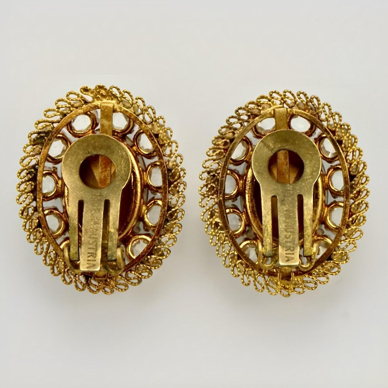 Austrian crystal gold plated oval clip on earrings. The beautiful crystals have a lovely filigree setting. Measuring length 3 cm / 1.1 inches by width 2.4 cm / .9 inch.
 
These are stylish and elegant earrings with sparkling clear crystals. Circa