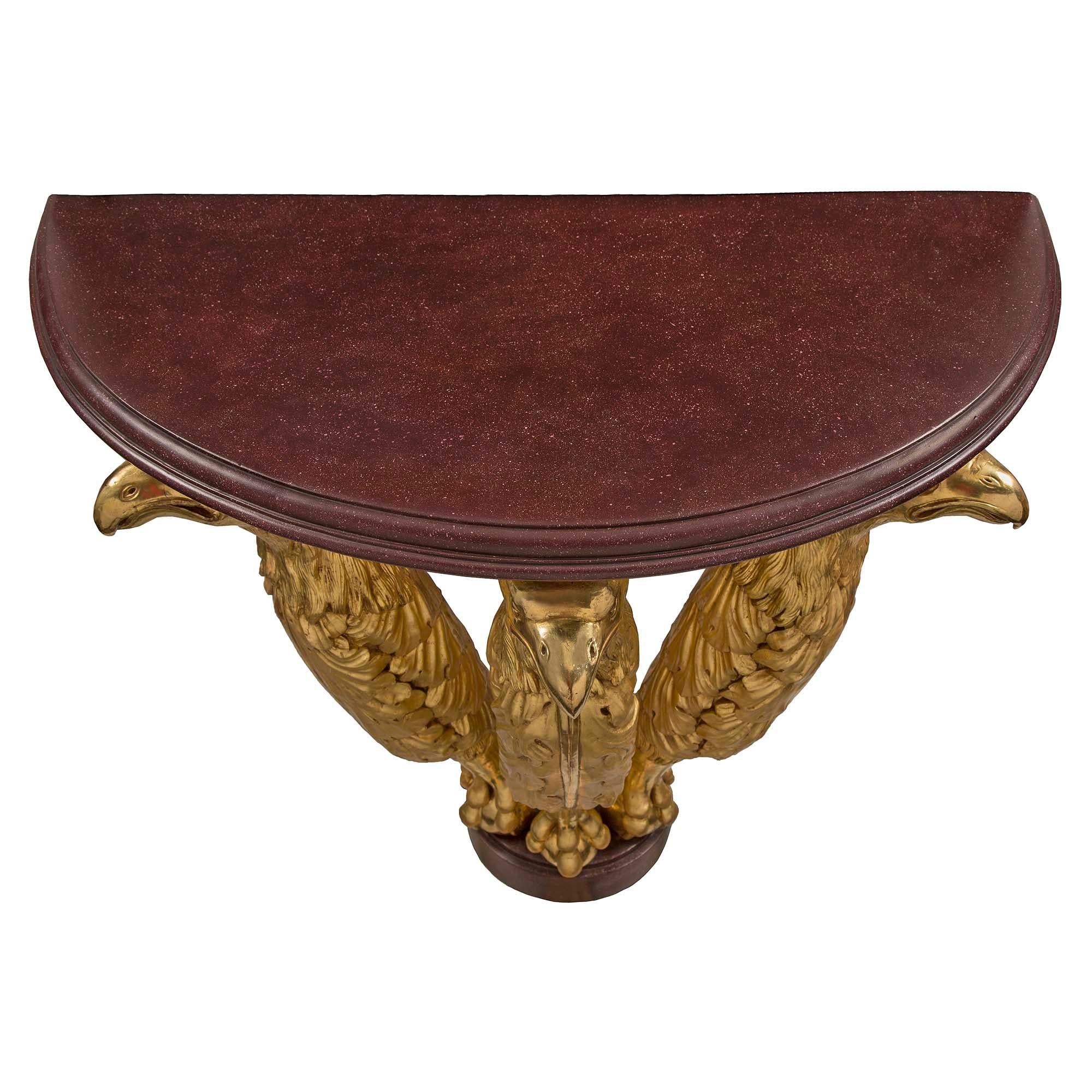 A rare and very unique Austrian early 19th century Neo-Classical st. giltwood and faux Porphyry demi lune console. This wall mounted statement making console is raised by a beautiful faux Porphyry mottled base. The central supports are three