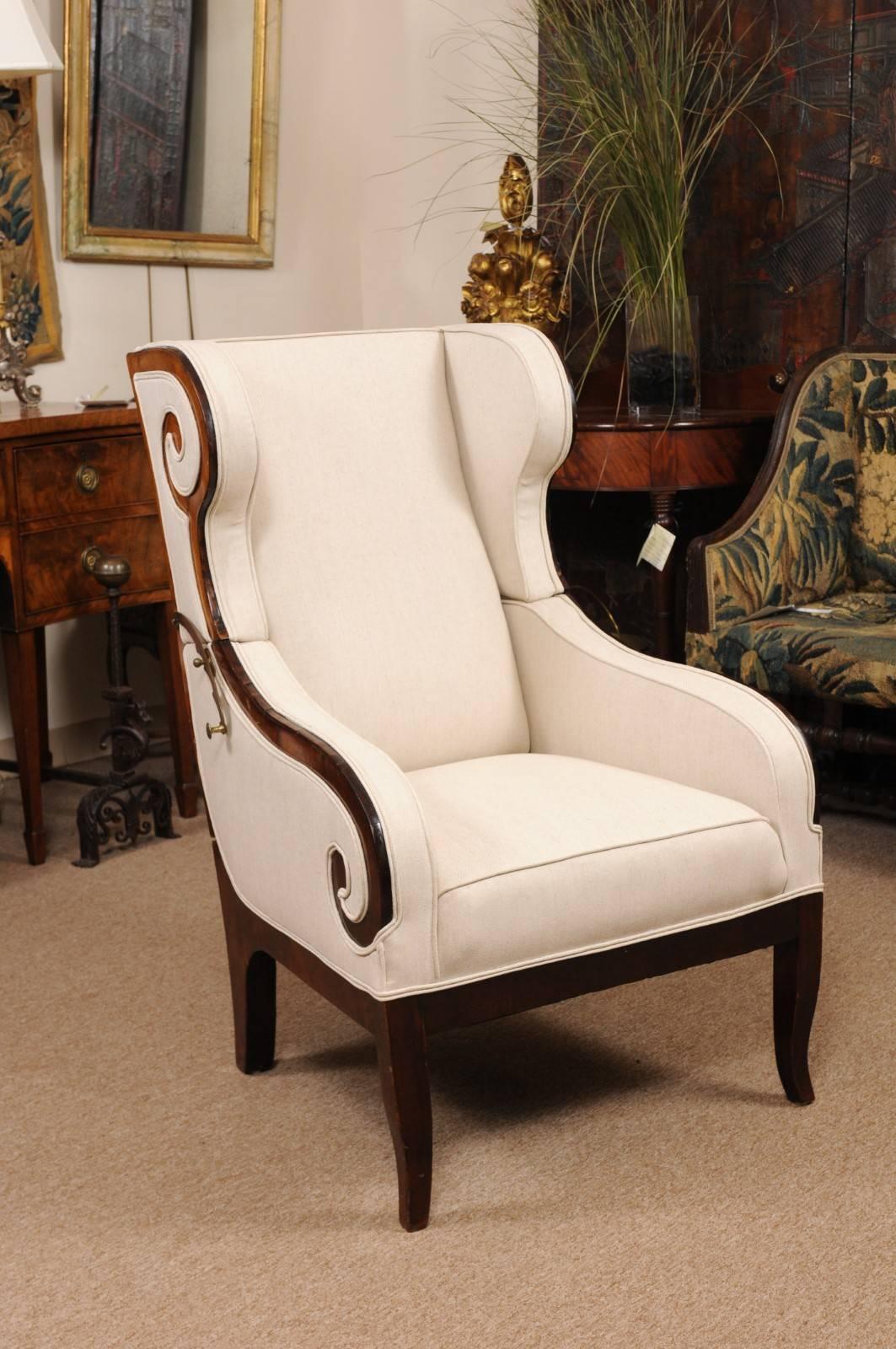 The Austrian bergere recliner in mahogany and linen upholstery with double scroll detail and splayed legs.