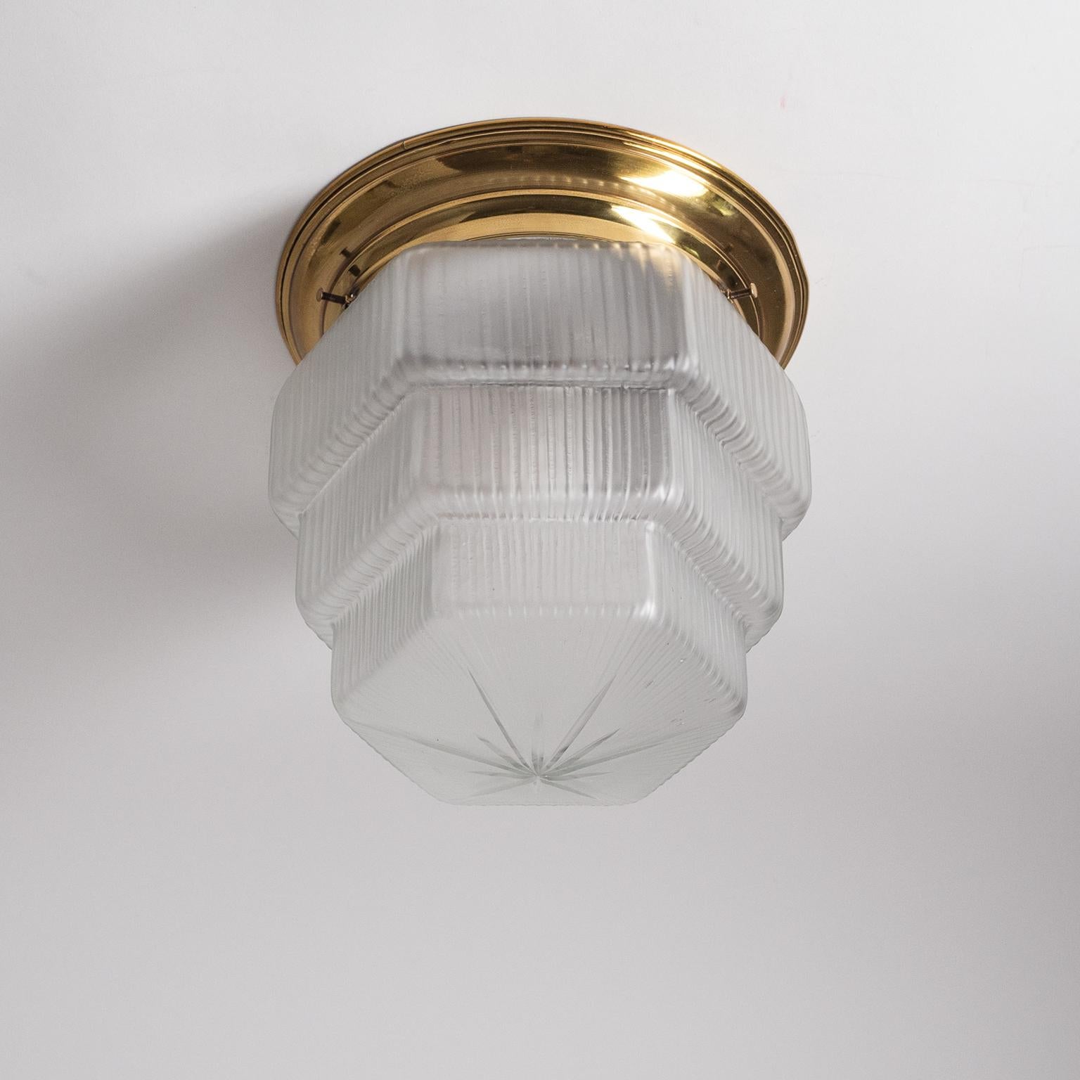 Rare Austrian brass and glass flush mount from the 1920-1930s. Brass backplate with an unusual, tiered, ribbed and cut glass diffuser with a satin finish. One original brass and ceramic E27 socket with new wiring.