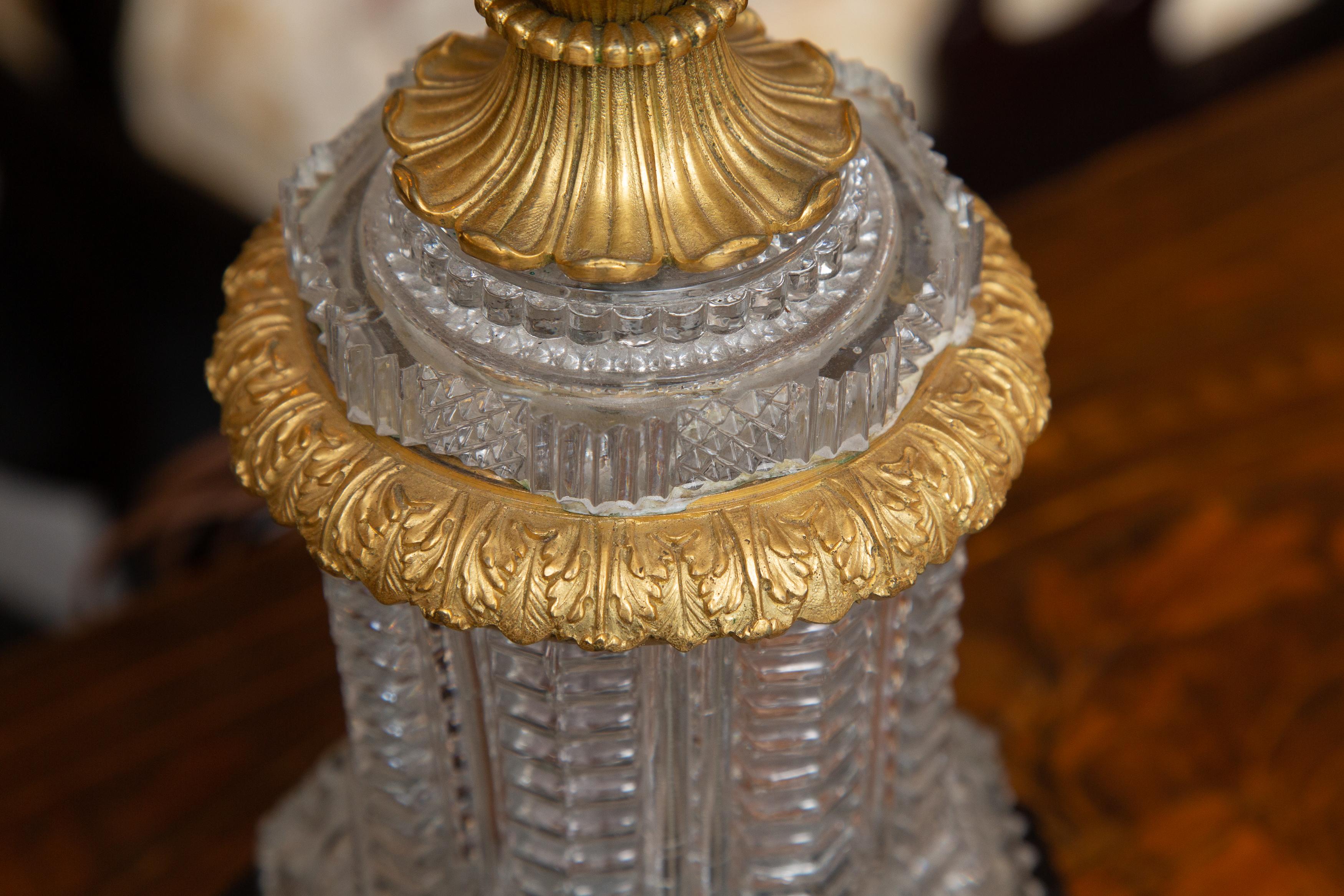 This is an elegant Austrian gilt bronze mounted cut crystal table lamp situated on an octagonal ebonized wooden base, 20th century.