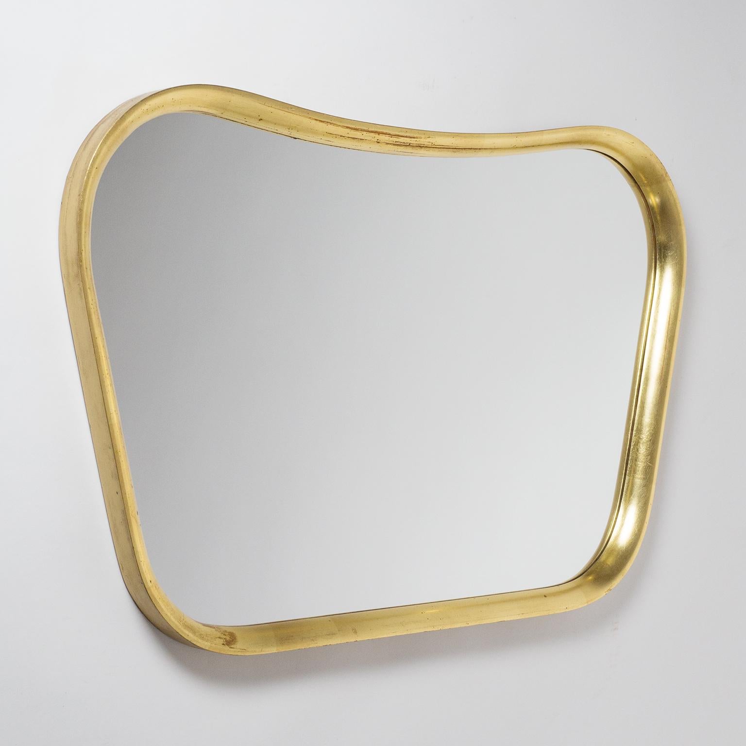 Lovely Austrian giltwood mirror from the late 1940s or early 1950s. Curved and sculpted solid wood frame with leaf gold finish. Nice vintage condition with some wear to the gilding and dryness to the wood.
