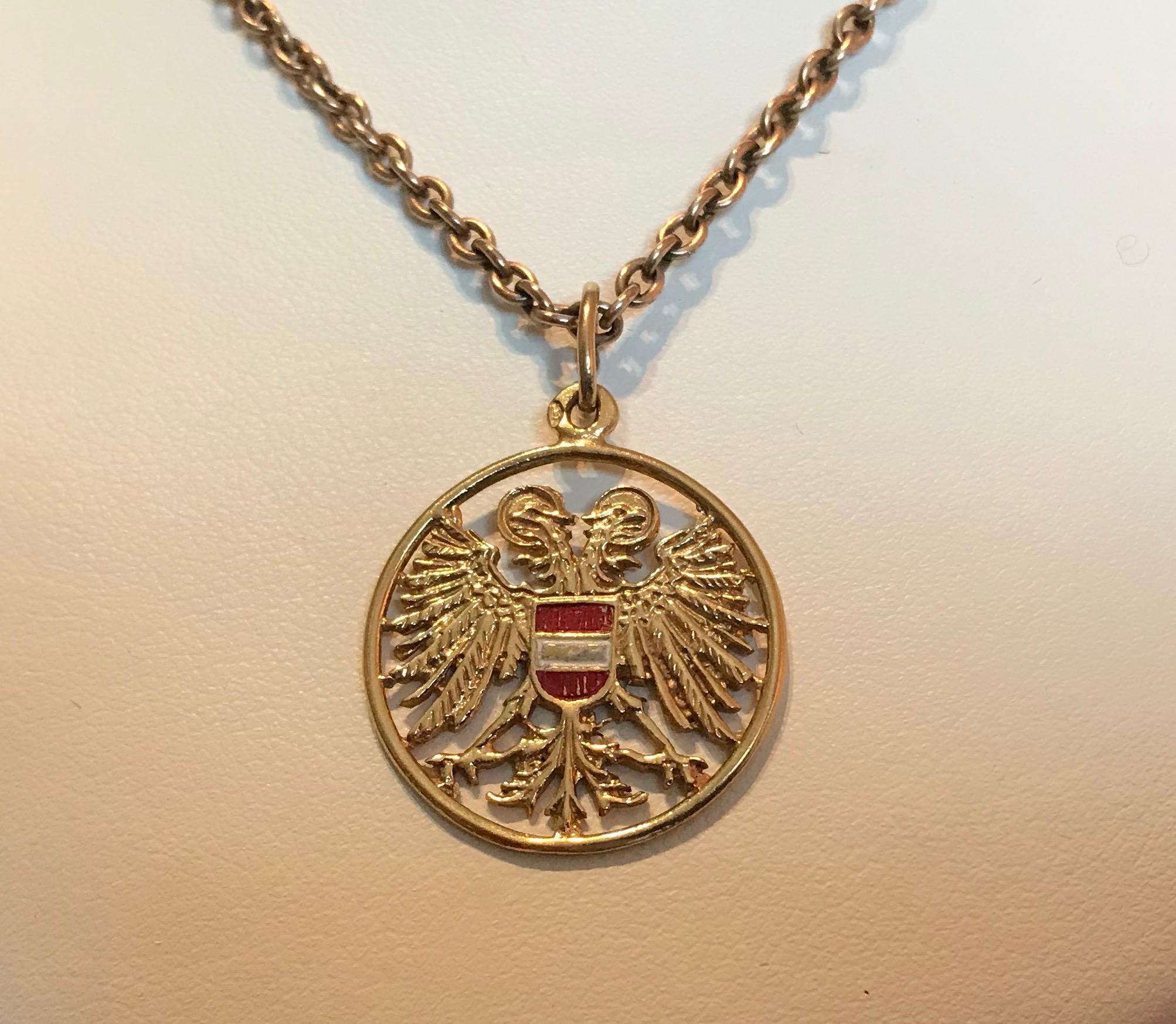 Of openwork gold design, the Habsburg double-headed eagle with outspread wings, centering a red and white enamel shield for the colors of Austria, finished on both sides, with oval suspension ring. 

1 1/8 in. (2.9 cm) long, including suspension