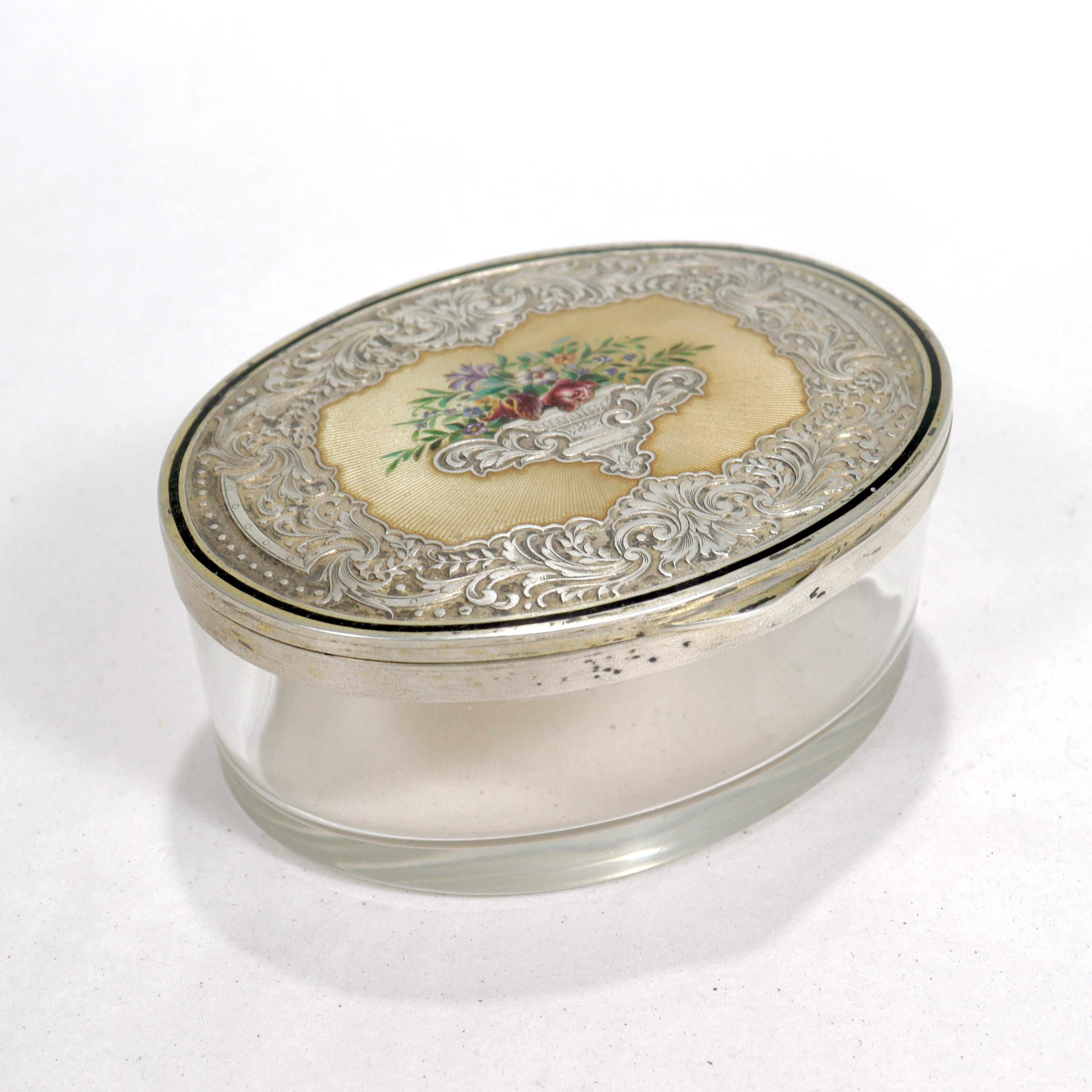 A fine antique Austrian glass, silver, & enamel table or dresser box.

By Georg Adam Scheid.

With a cornucopia or vase form decoration enamel flowers in a guilloche cartouche. The rest of the lid has an ornate pattern etched in the silver.

Marked