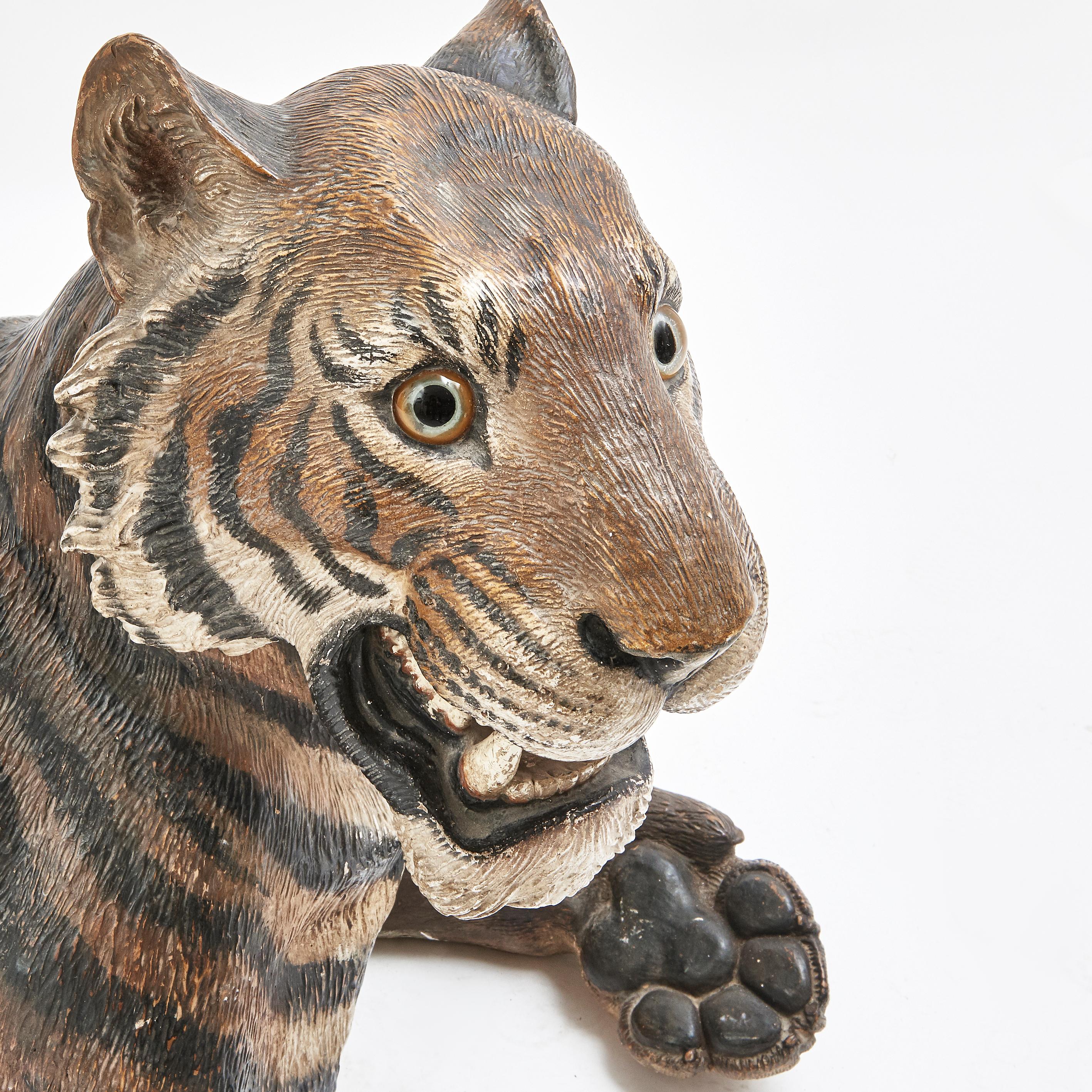 Very rare and large cold painted terracotta model of a recumbent tiger, with paws outstretched and glass eyes. Austrian, late 19th century, old repairs. His coat in traditional tiger colours of deep amber and black stripes, mouth open bearing his