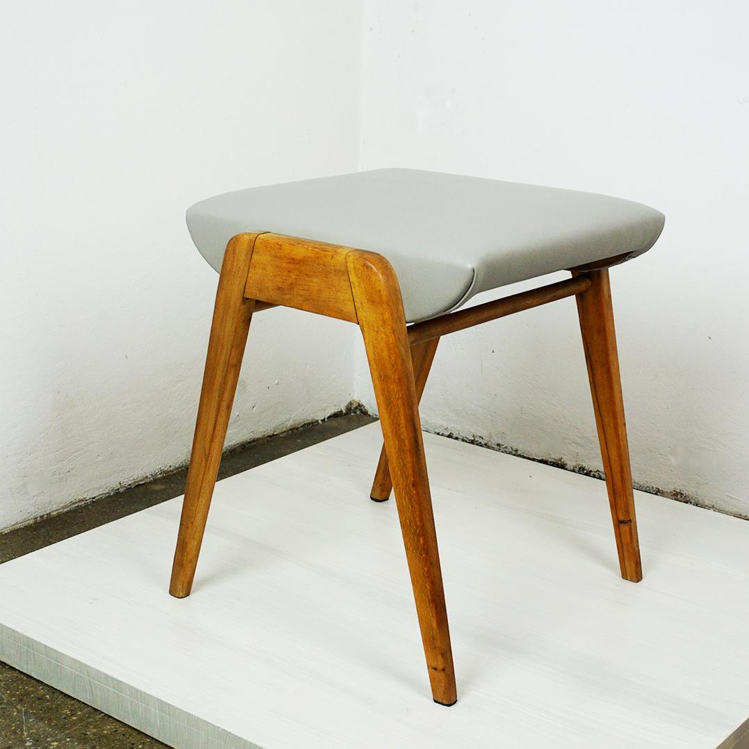 Este taburete austriaco vintage de mediados de siglo de madera de haya y cuero gris renovado fue diseñado por Franz Schuster y producido por Wiesner Hager en Viena. 
Presenta un armazón de madera de haya y un asiento revestido de cuero gris
