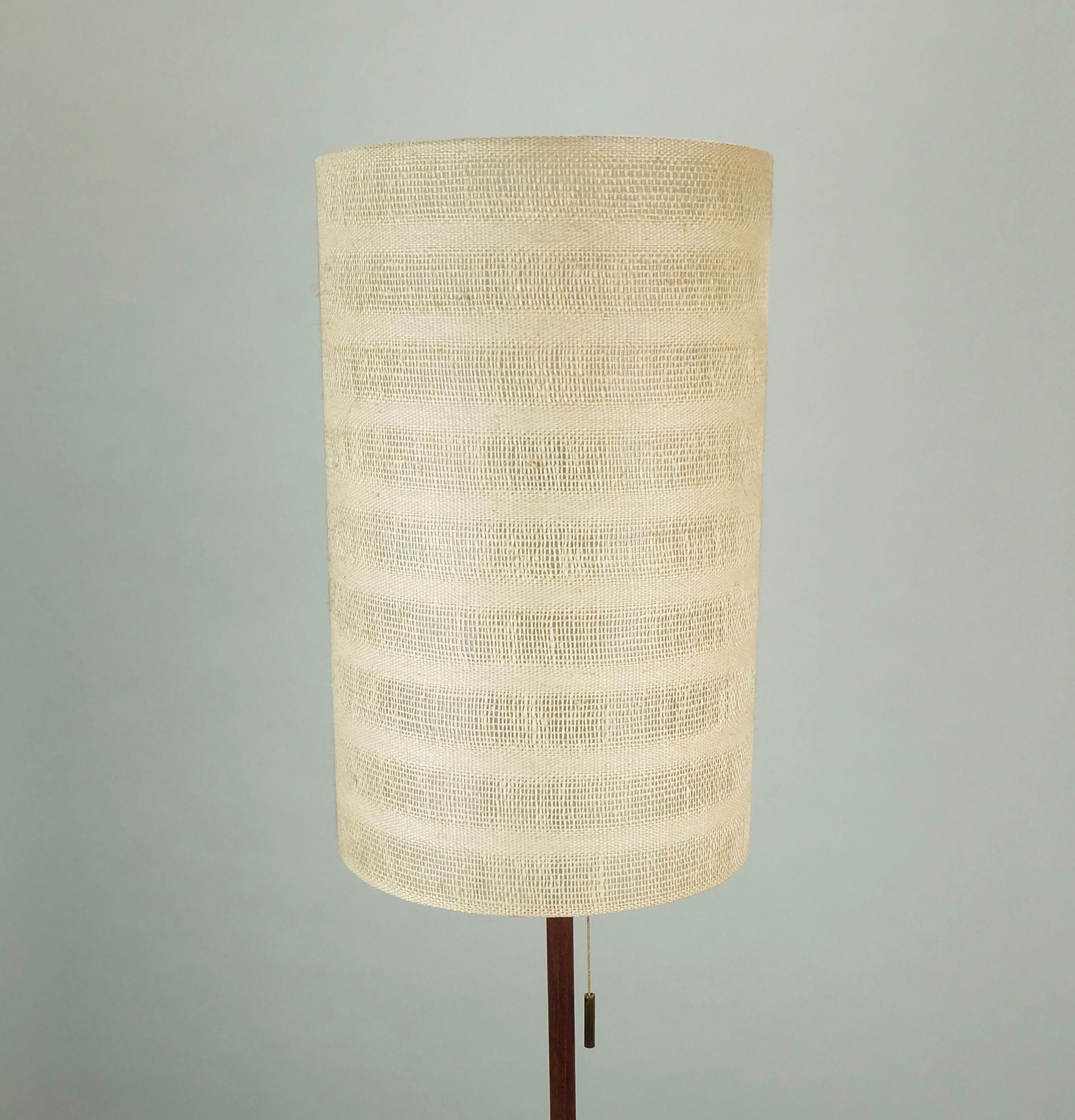 Bellissima lampada da terra austriaca di metà secolo. Design Julius Theodor Kalmar, anni '50. Base a treppiede in ottone e legno di teak. Il paralume è realizzato in carta e tessuto. Contiene 1 lampadina E-14. 
Un'aggiunta perfetta a qualsiasi