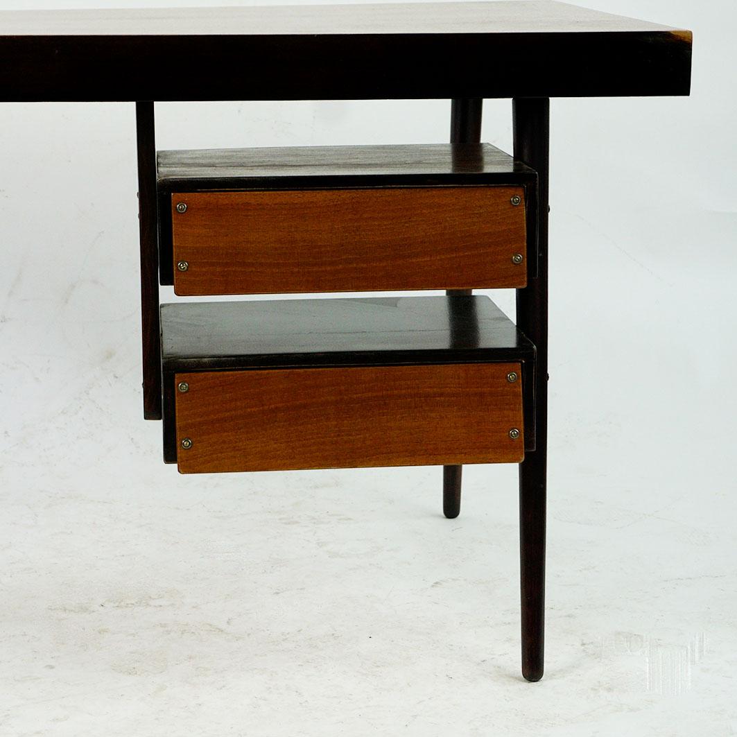 Very charming small Mid-Century Modern teak desk designed and manufactured by an Austrian Post war Architect. It features a teakwood floating top with slightly taperd legs and a unit with two drawers.
The wood has been slightly restored, the right